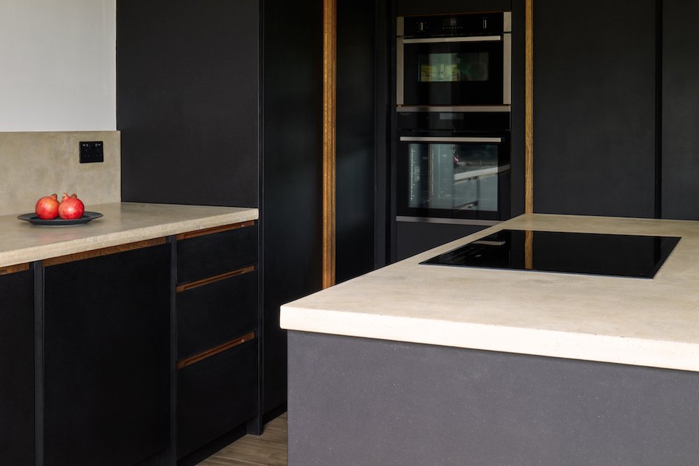 Bespoke dark black kitchen cabinetry with oak handles and hand-cast concrete worktops in Dartmouth, Devon