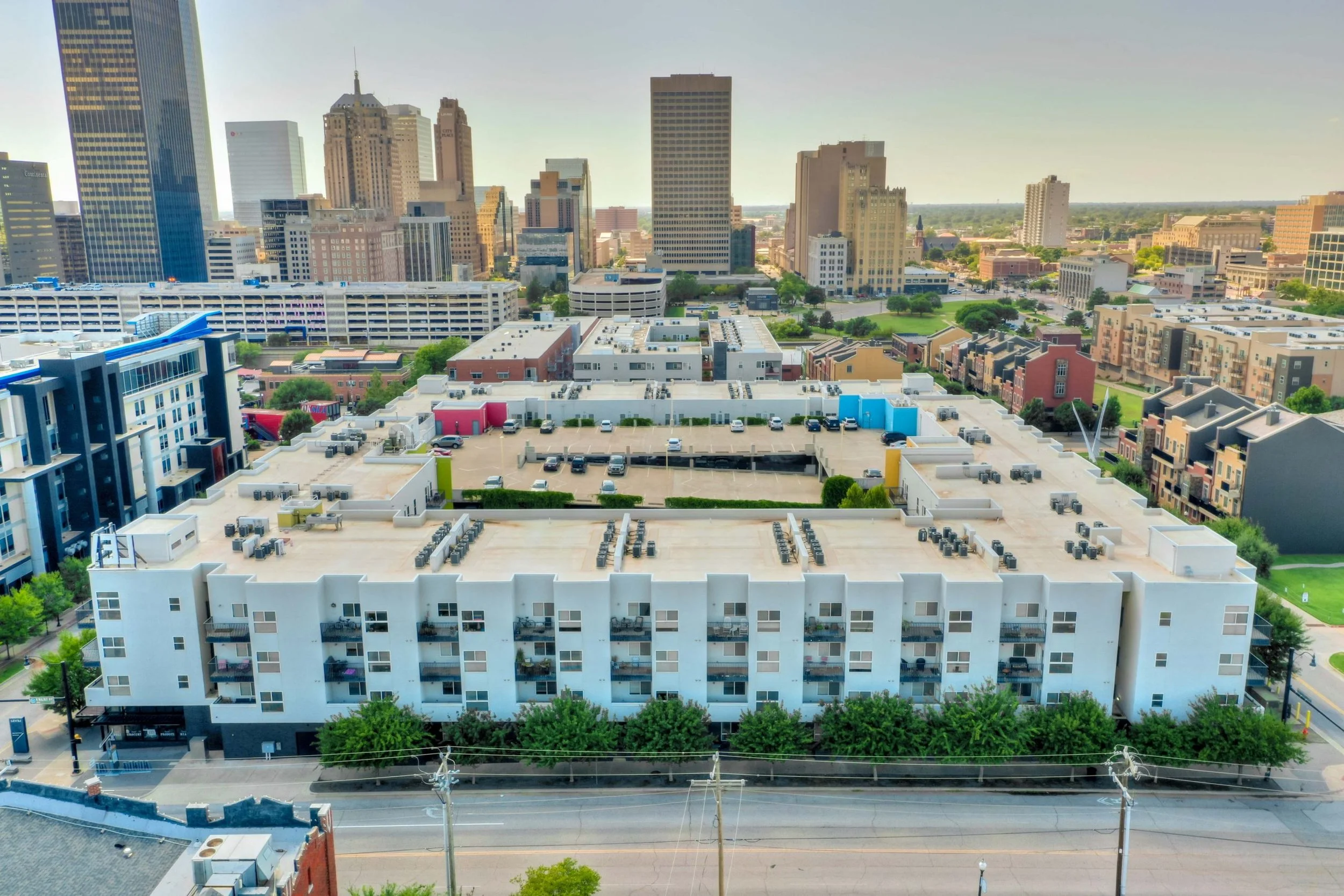 A cityscape view from above showing a parking lot, modern buildings, and a skyline with skyscrapers in the background.