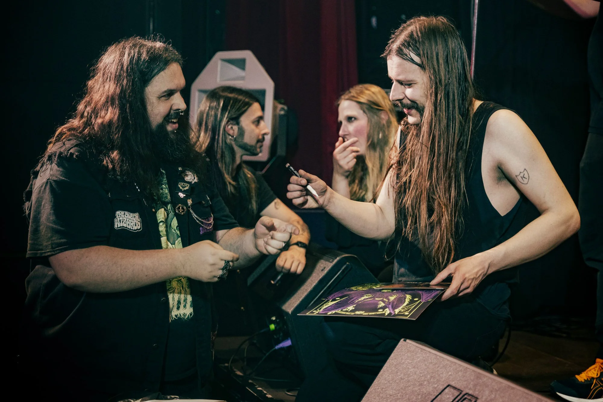 band members signing merchandise for fans after concert
