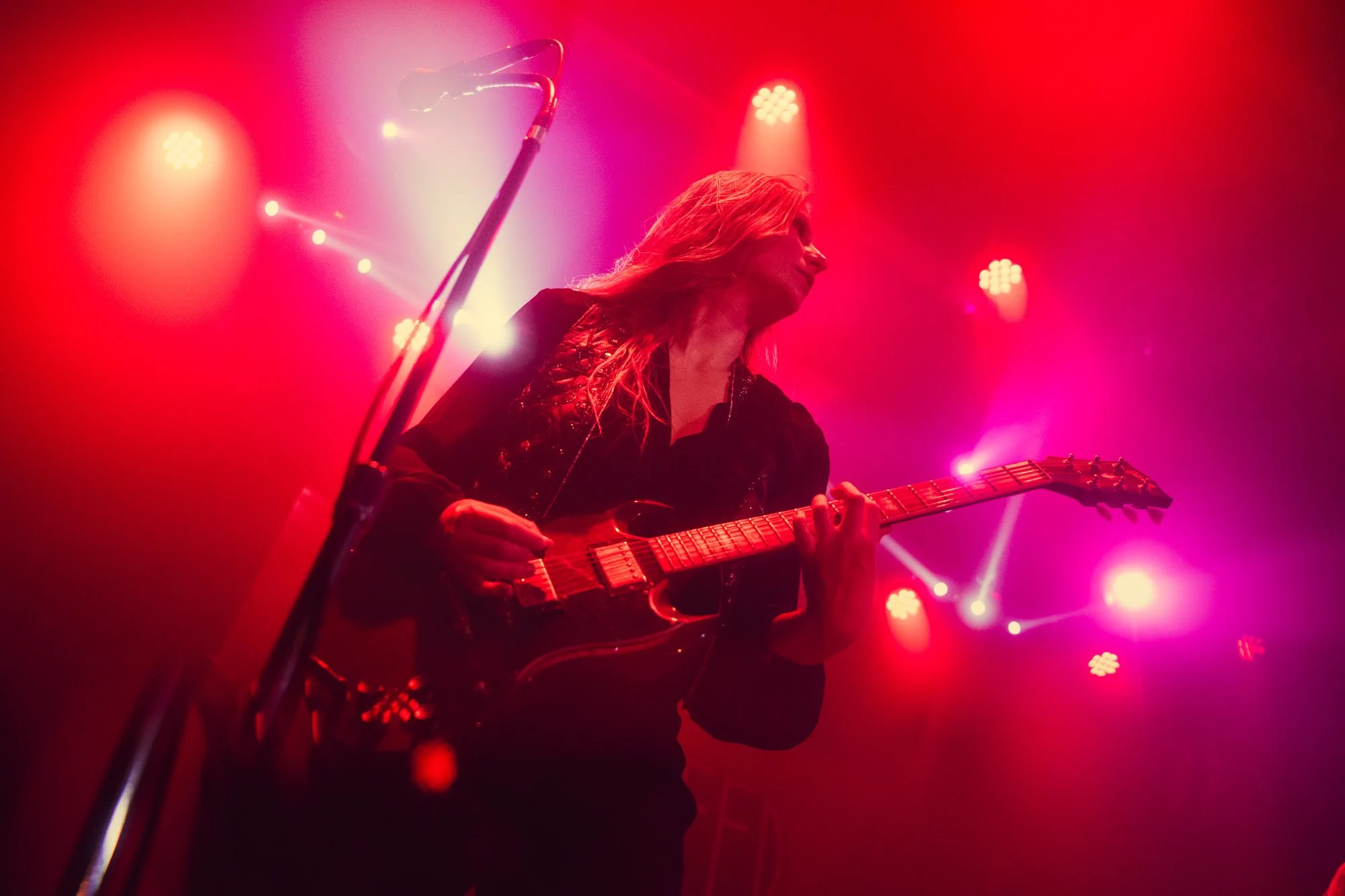 guitarist playing solo under red and purple stage lights
