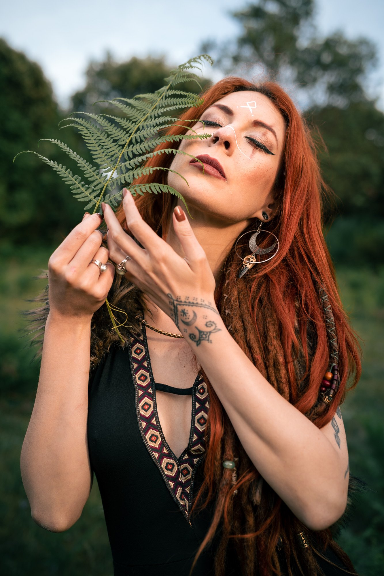 Pagan Nordic portrait of Susan Lenoir with Viking rune makeup and black dress, interacting with fern leaves in the Montseny mountains, Catalonia.