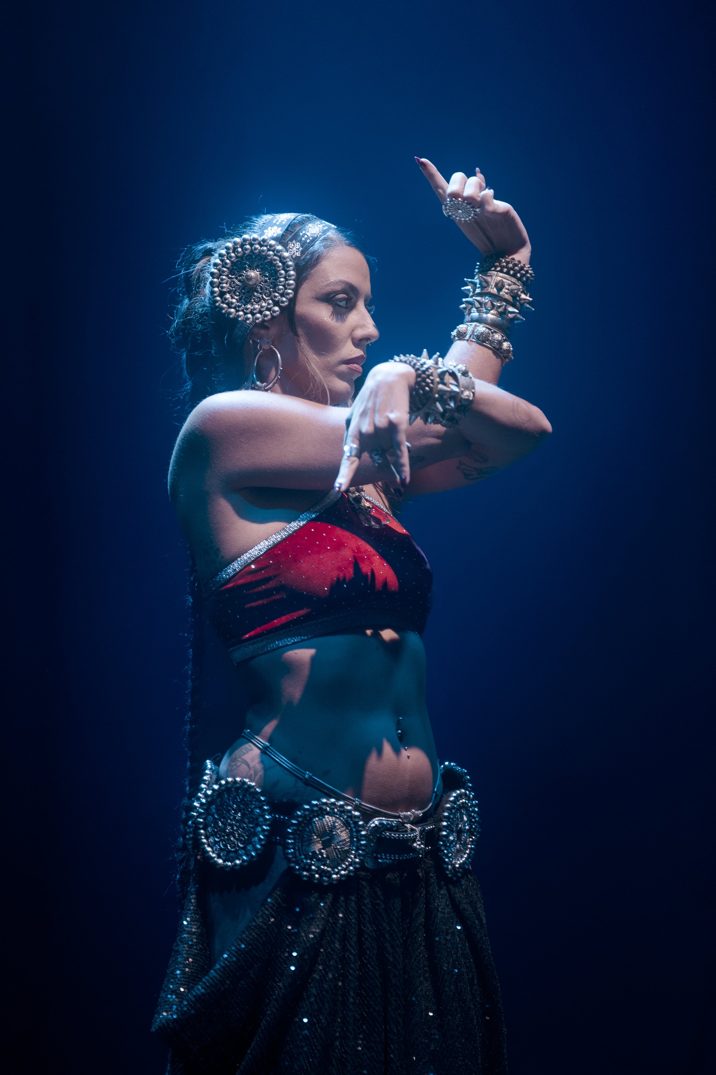 Lia Clars performing tribal fusion dance under blue stage lighting.
