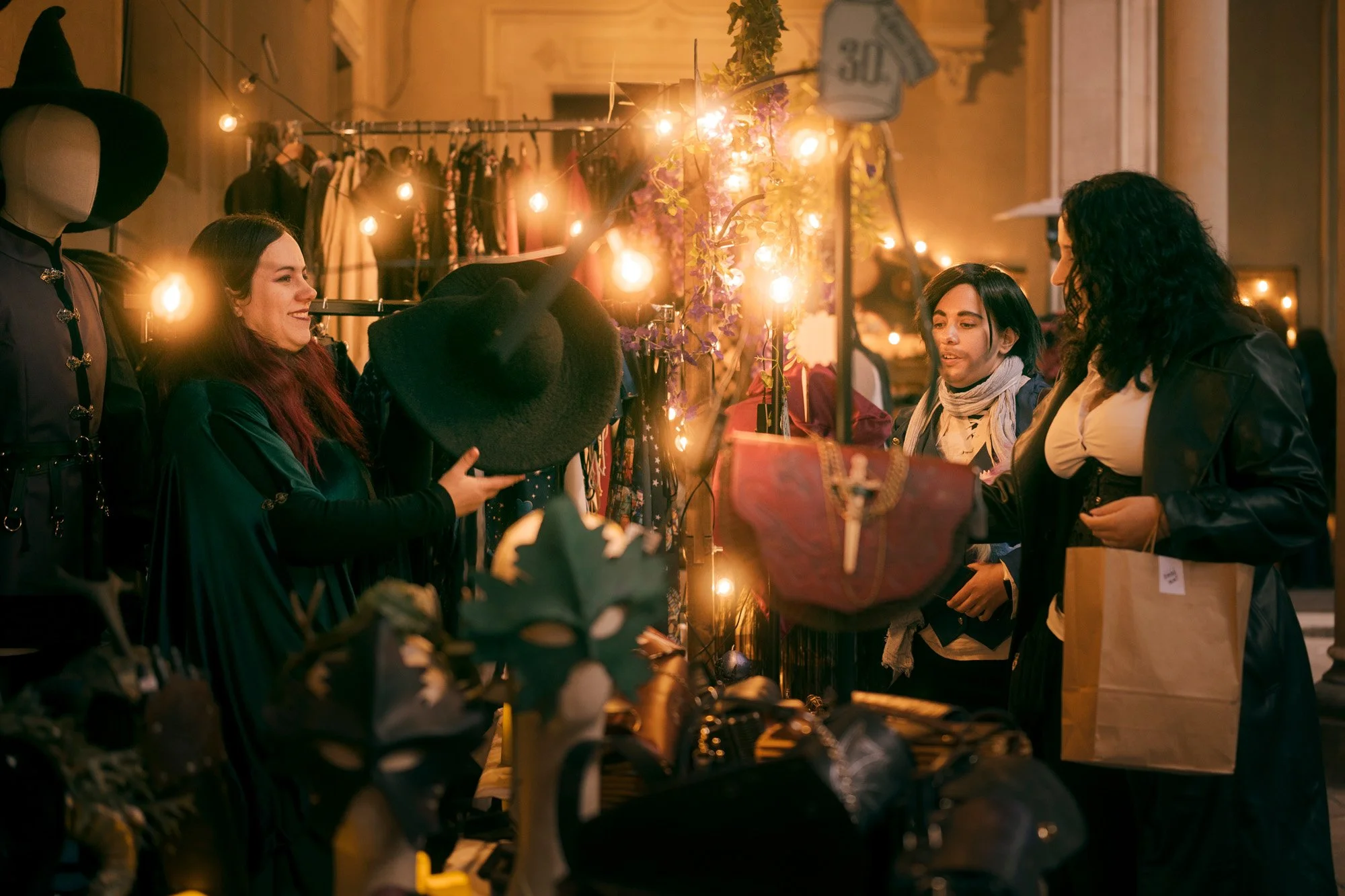 Cosplayers interacting at the Witch Market Barcelona, surrounded by warm lights and handcrafted fantasy decorations.