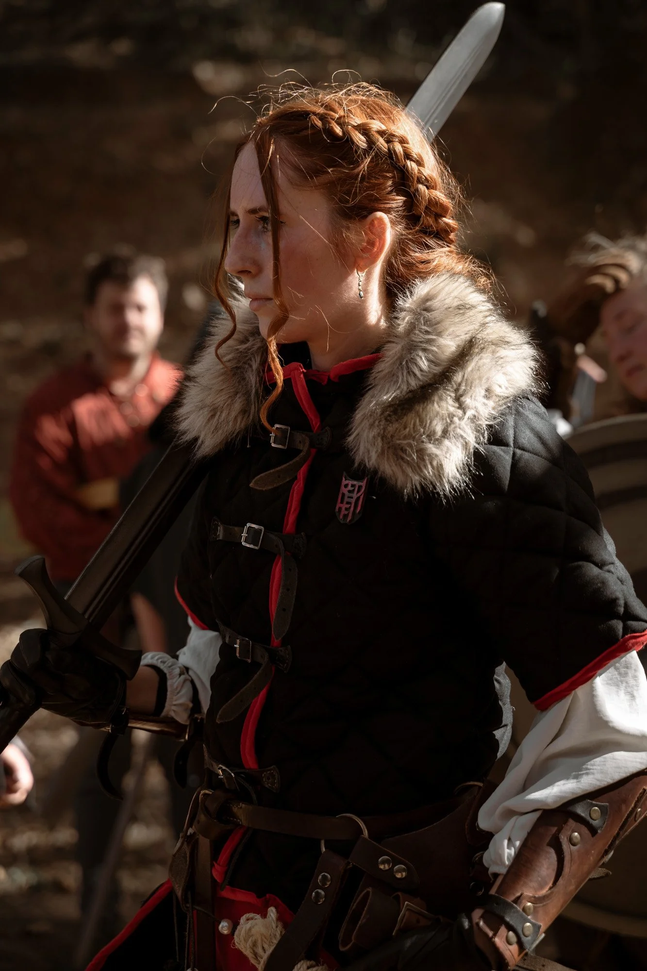 Female LARP character in medieval-inspired armor photographed during a live action role play event in a forest setting.