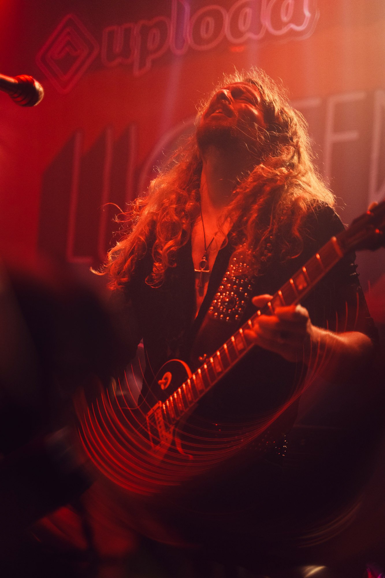 guitarist playing under red stage lights during rock concert