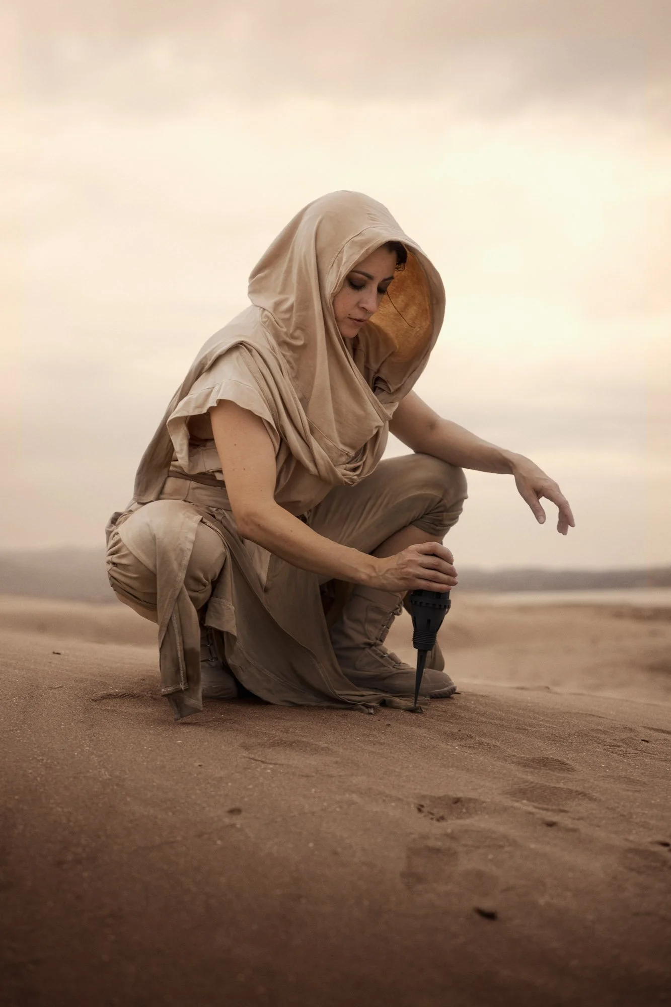 Lidia Martin crouching in the sand, searching for signs of a sandworm