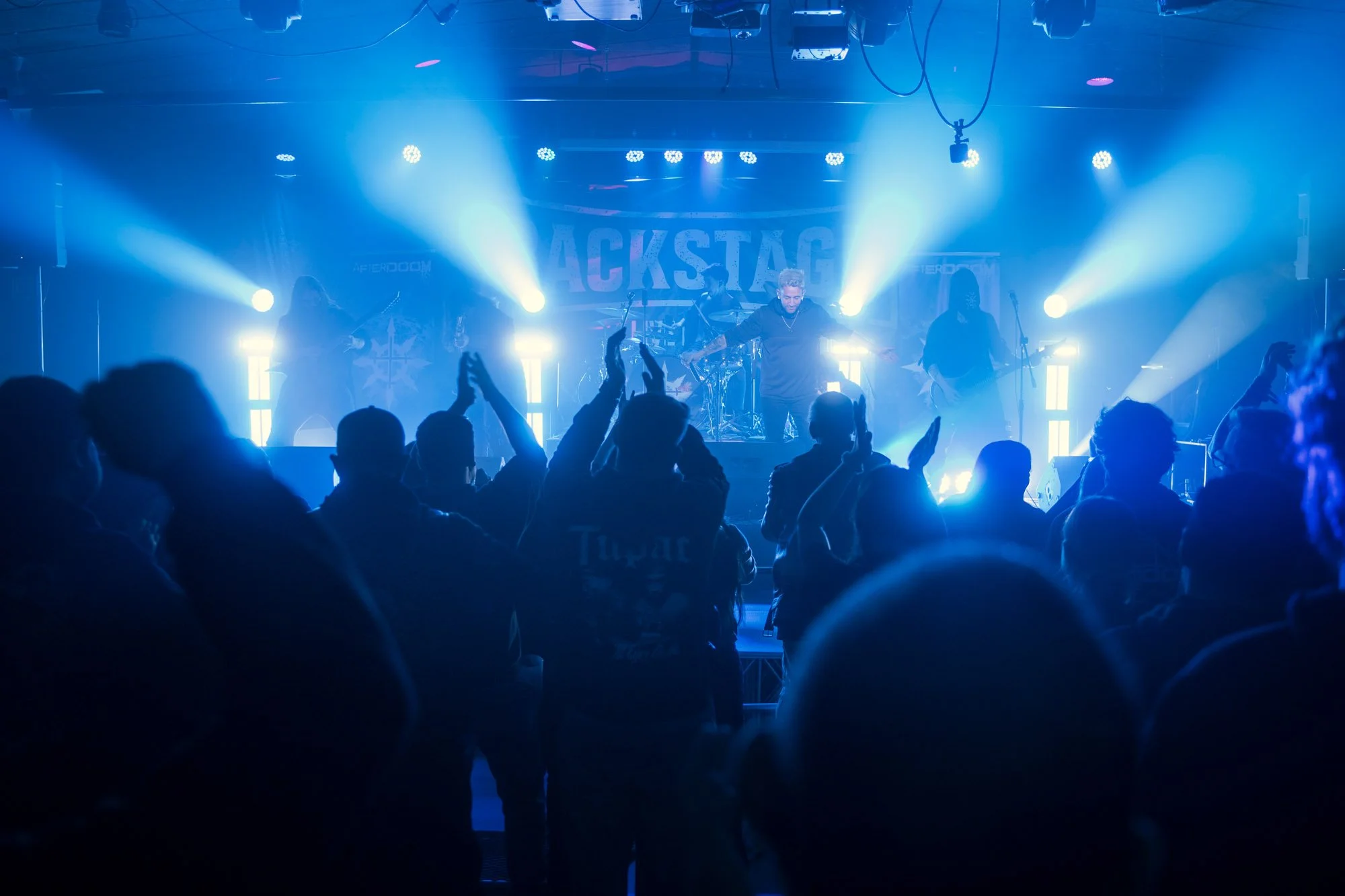 wide shot of stage and audience during metal festival with blue lighting