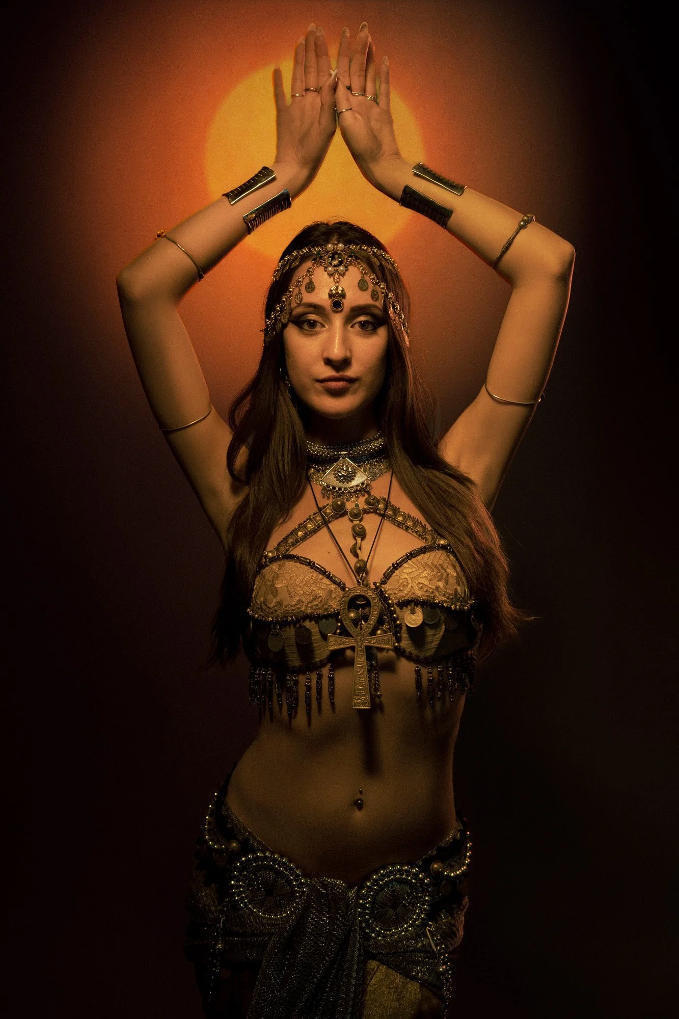 Tribal fusion dancer posing in studio with sun projection creating a golden halo effect.