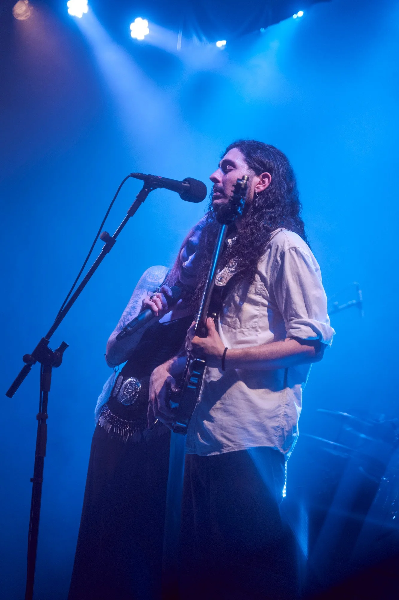 Kris Vega resting her head against the guitarist during an intimate moment of the Serapis Project live performance.