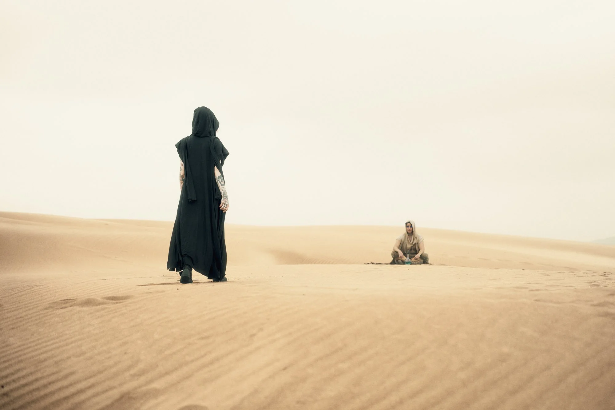 A Dune-inspired Reverend Mother approaching a Fremen wanderer across the desert