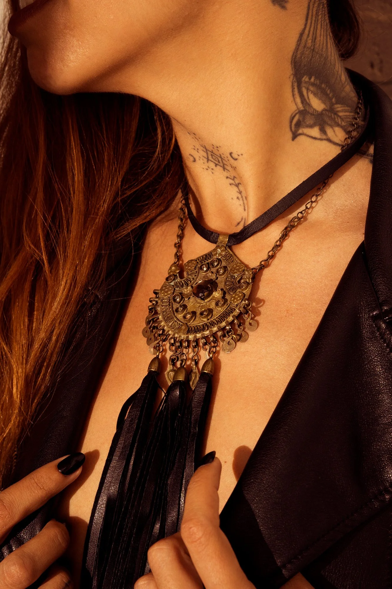 Boho industrial fashion portrait with layered jewelry and leather jacket under directional flash light.