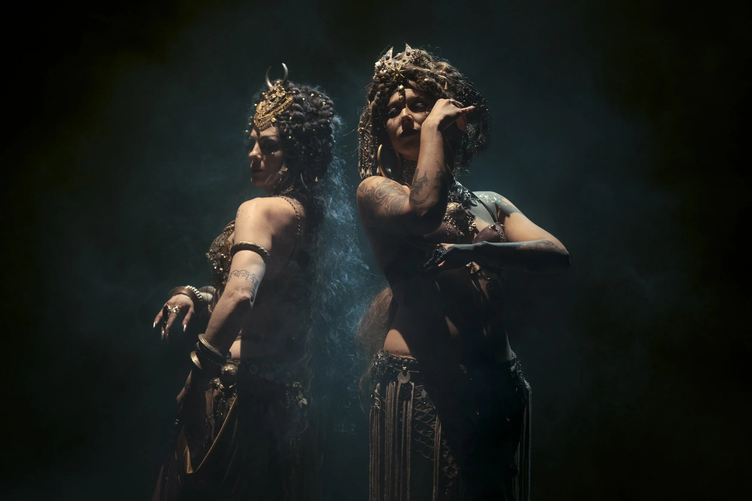Tiare Valouria and Cosmodaughter performing a tribal fusion dance duet in dramatic stage lighting.