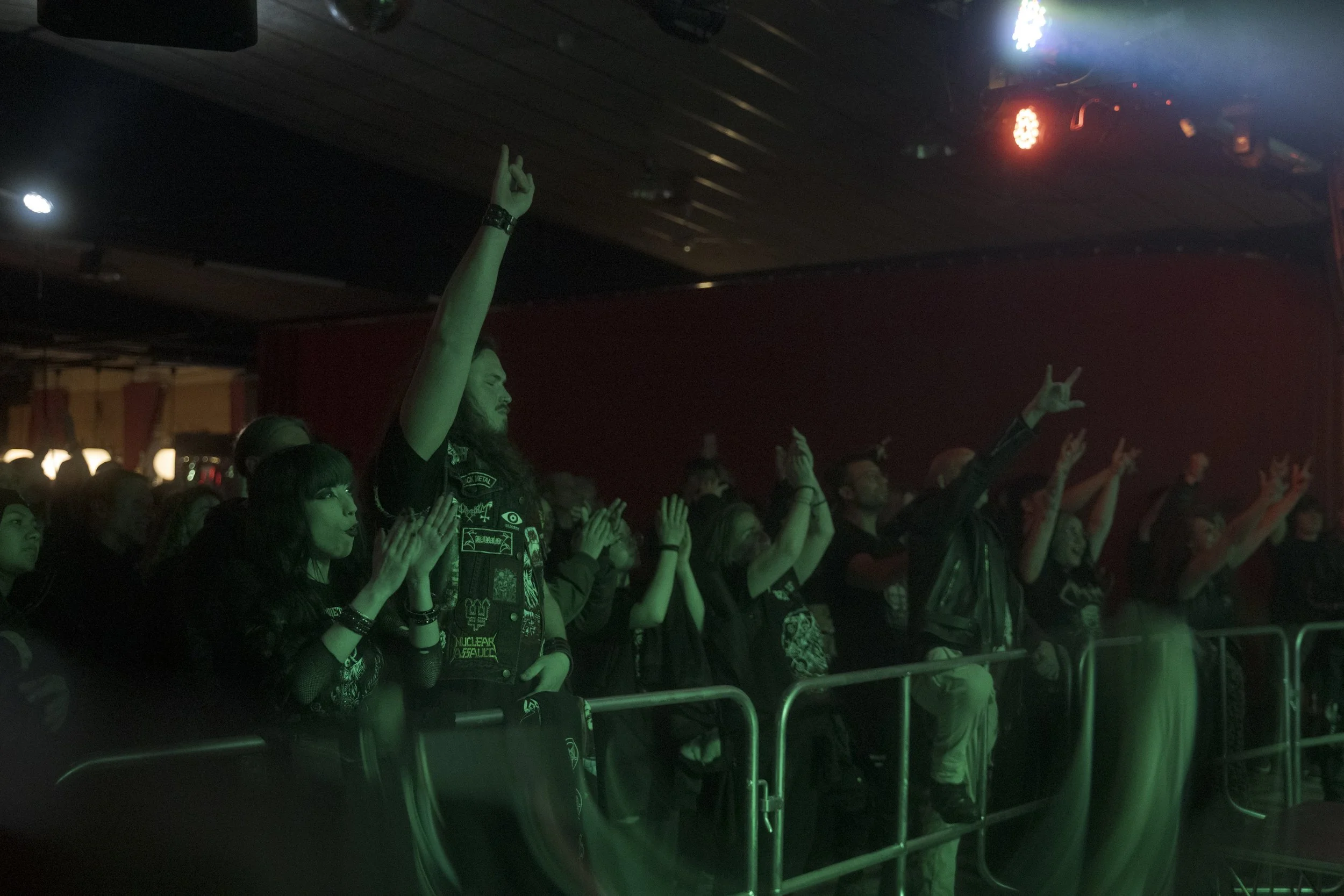 crowd raising hands during live metal concert near stage barrier