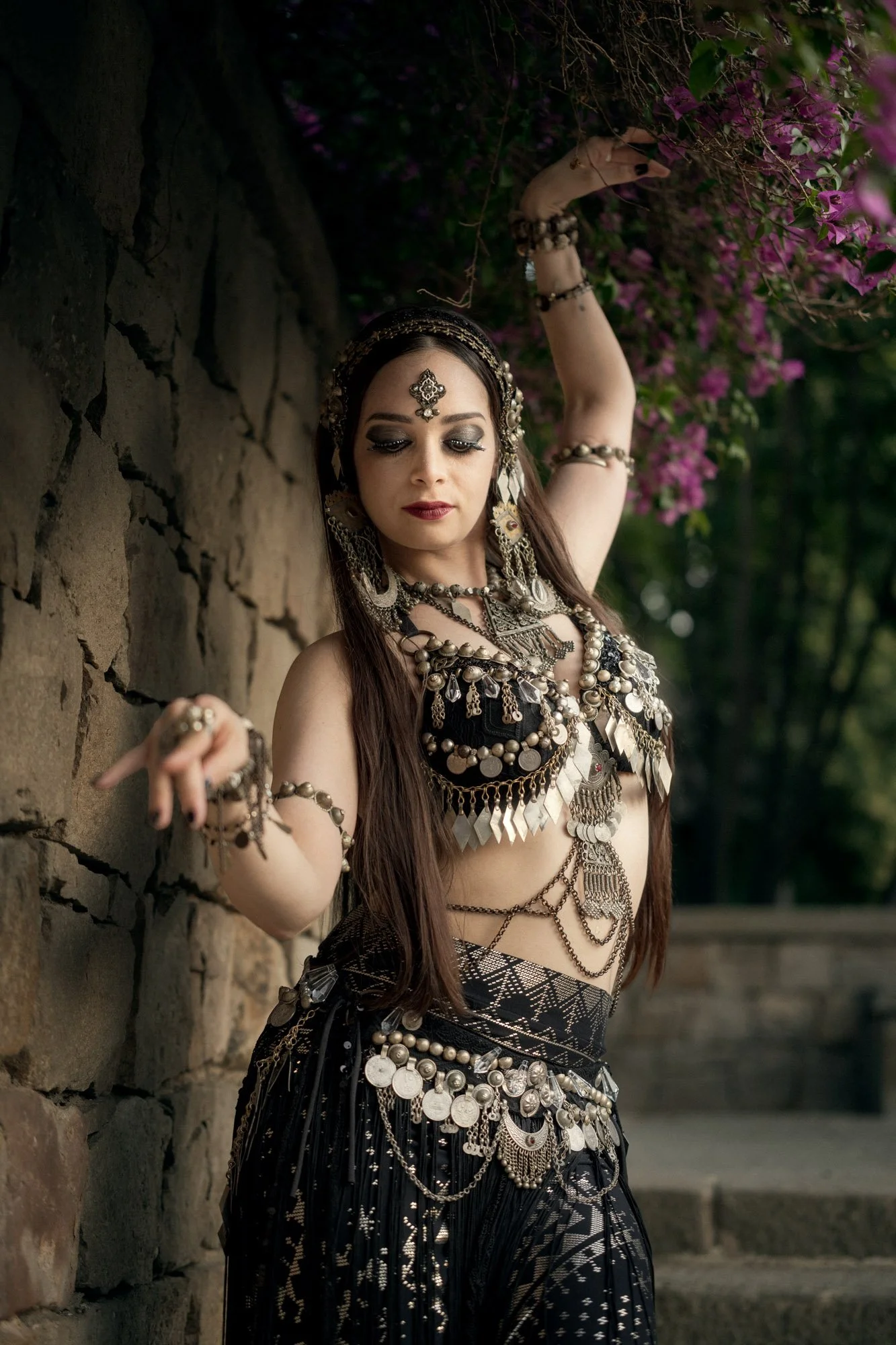 Michelle Bettridge performing a tribal fusion pose beside a stone wall in the Jardins de Laribal