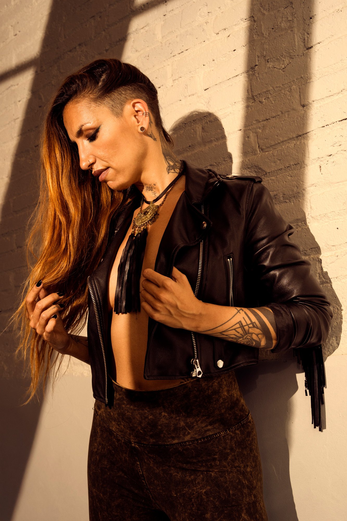 Boho industrial fashion portrait with layered jewelry and leather jacket under directional flash light.