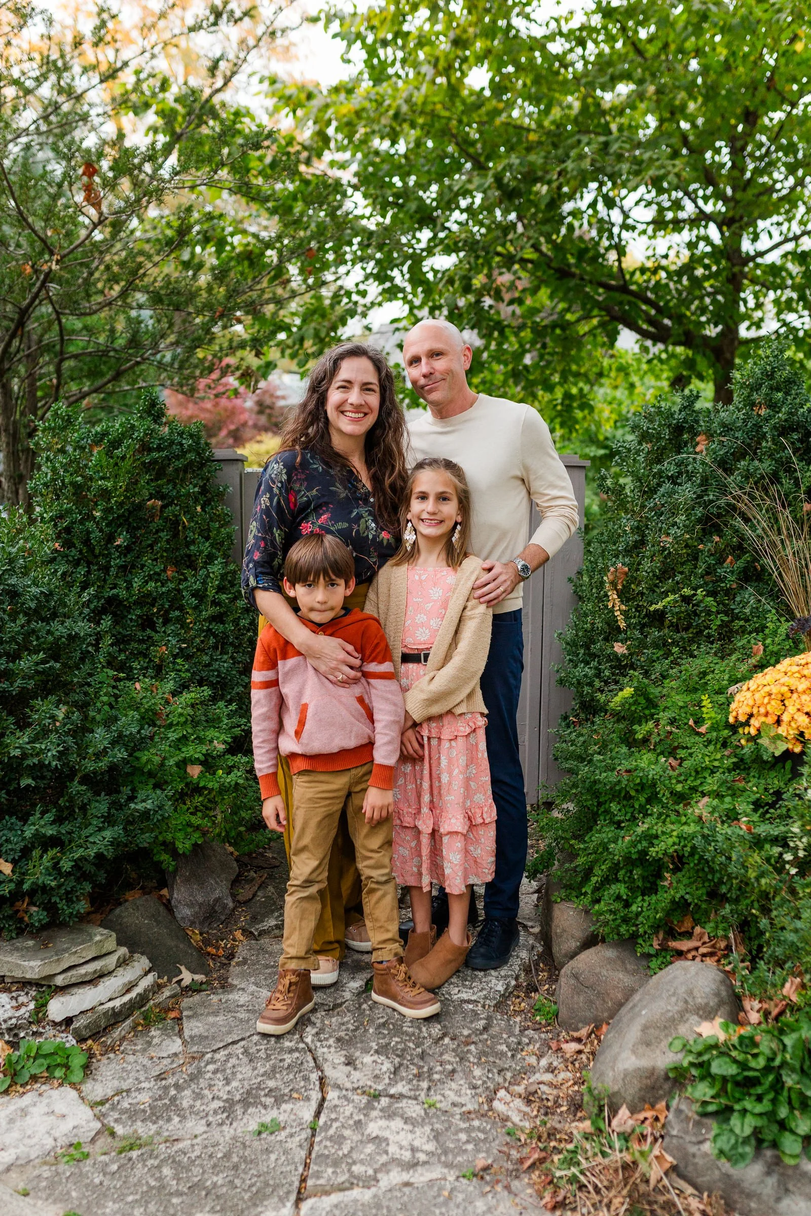 man woman boy girl posing for camera summer surrounded by bushes