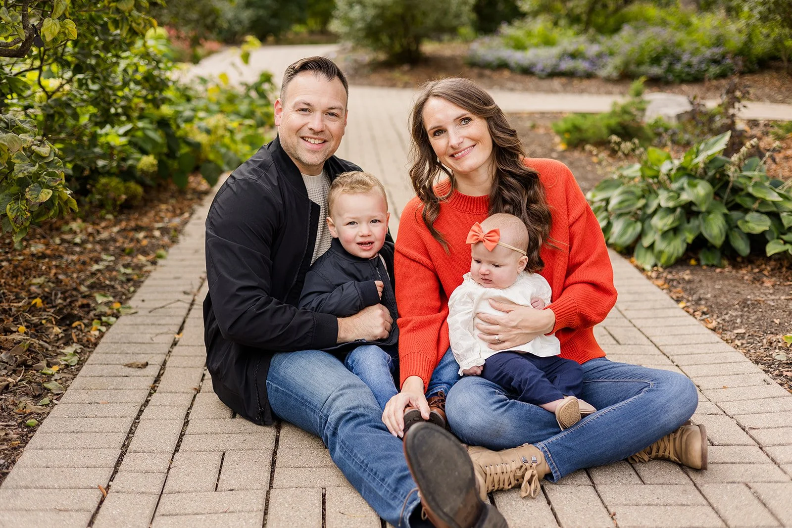 family of four sitting on a path in lilacia park lombard getting their photos taken