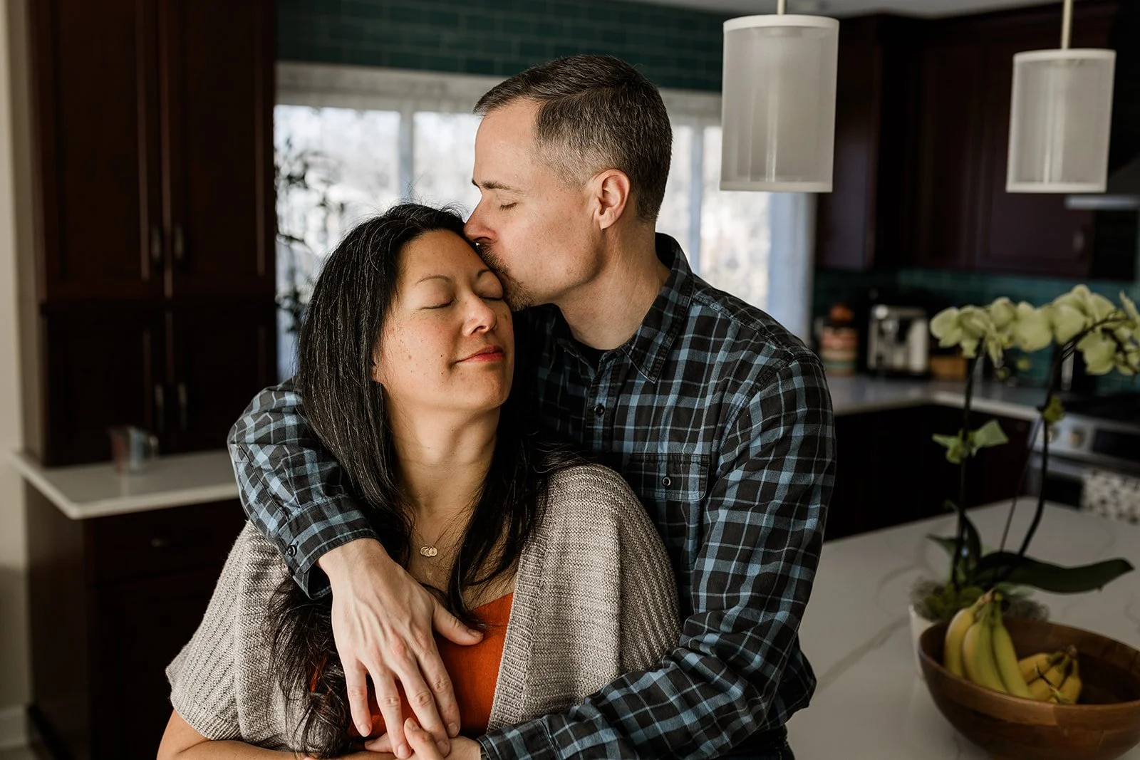 man holding woman while kissing her temple with both of their eyes closed