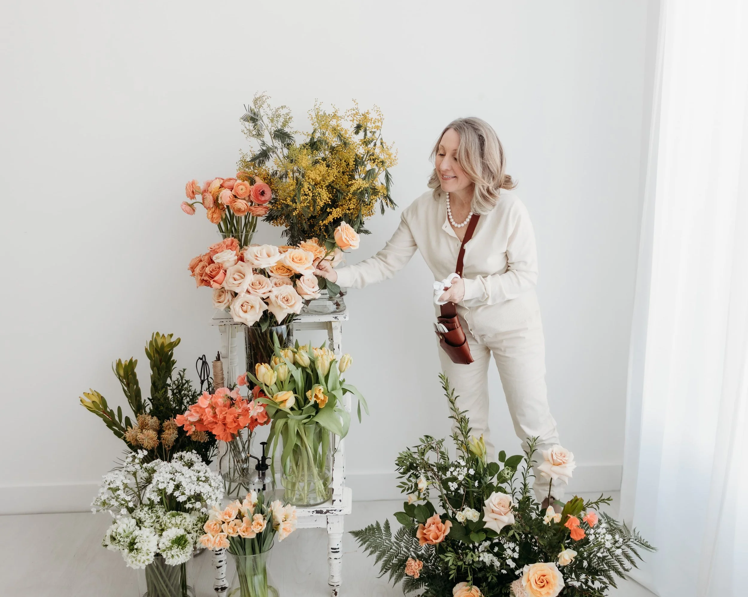 A Twig & Bloom florist in Victoria picking a rose from a vase. Flowers are arranged for a flower workshop in Victoria BC.