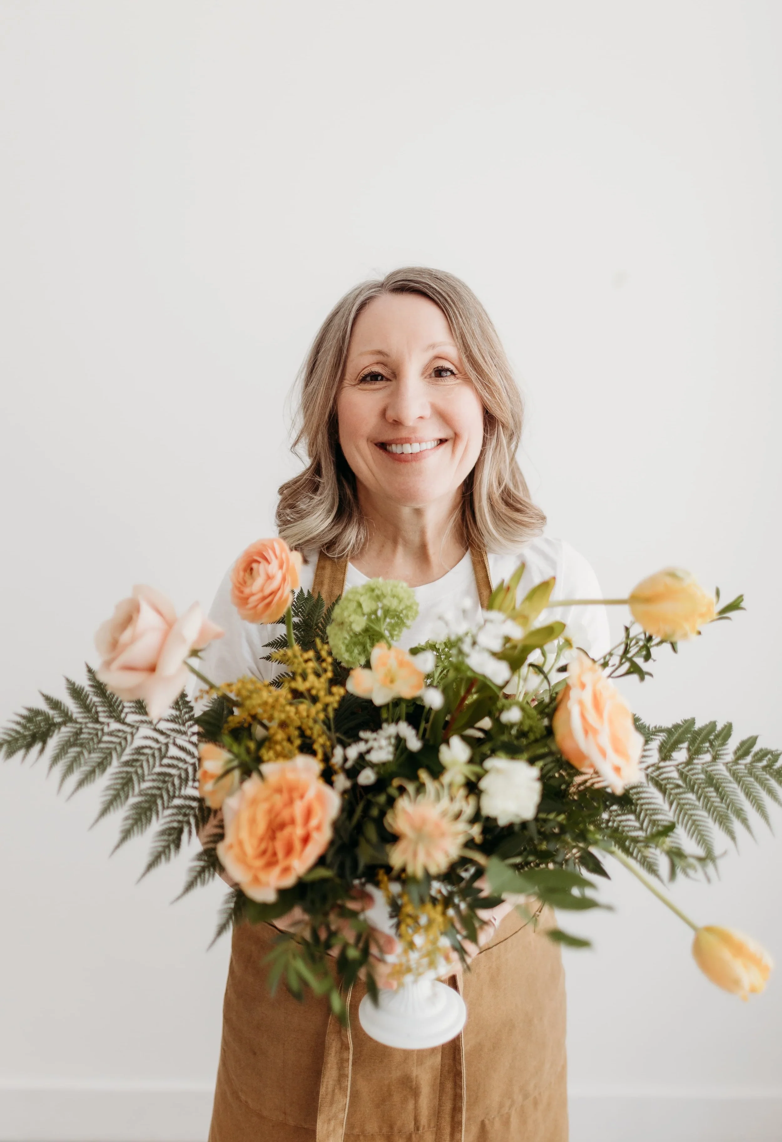 Twig & Bloom Victoria owner Ingrid holding a vase of peachy spring flowers.