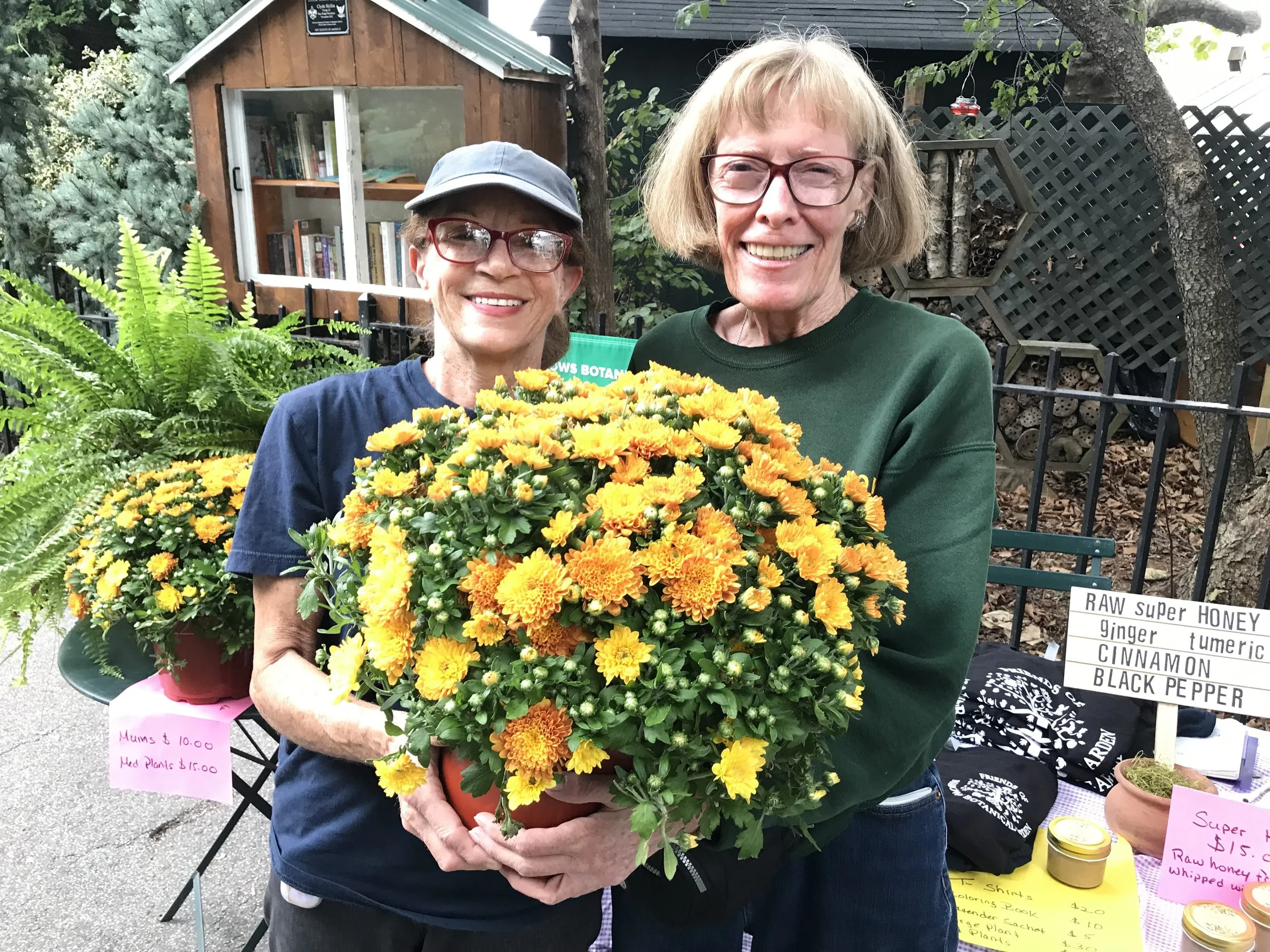Linda and volunteer holdin potted plant at plant sale event