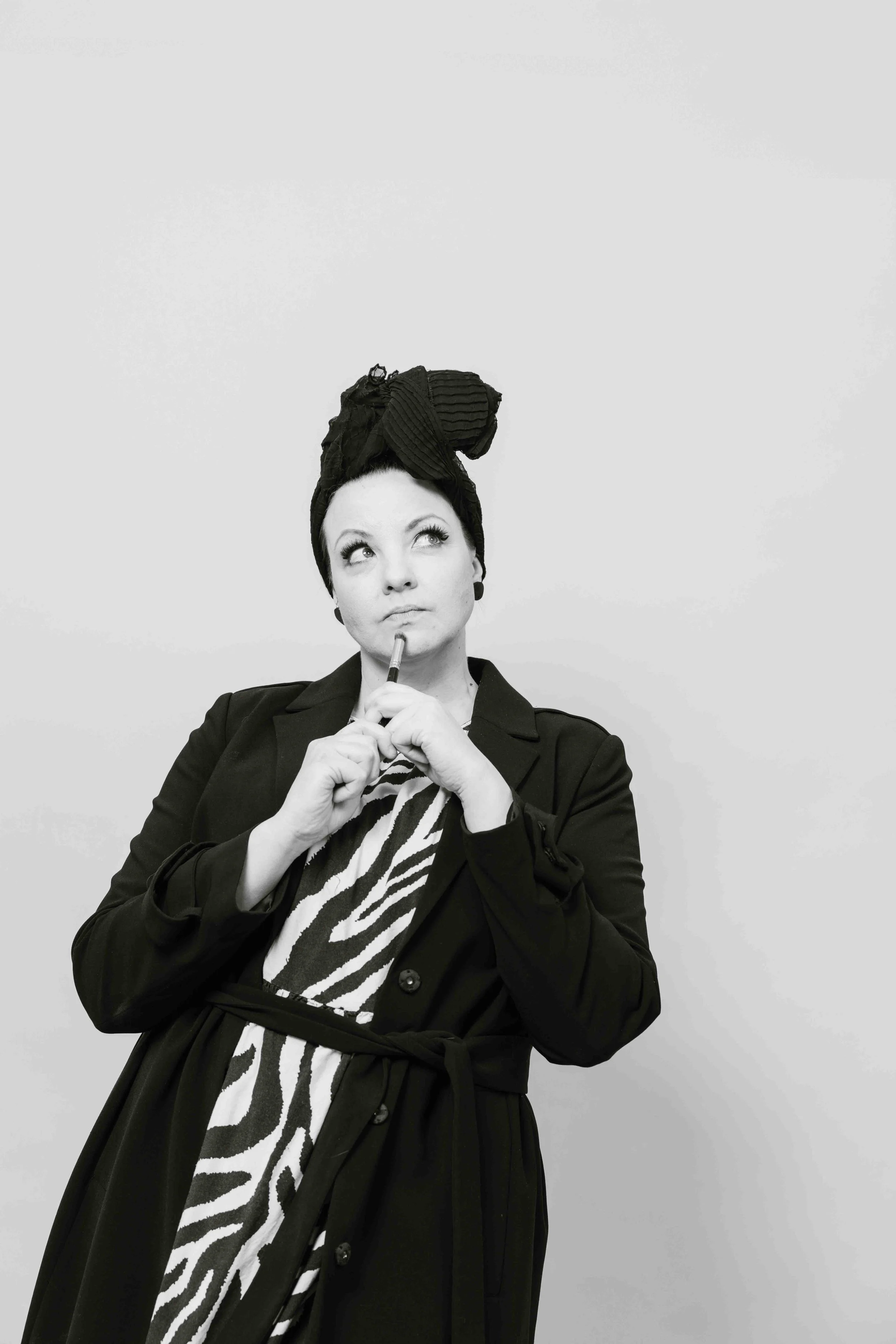 Mustavalkoinen valokuva naisesta, jolla on huivi päässään ja zeeprakuvioinen mekko.
