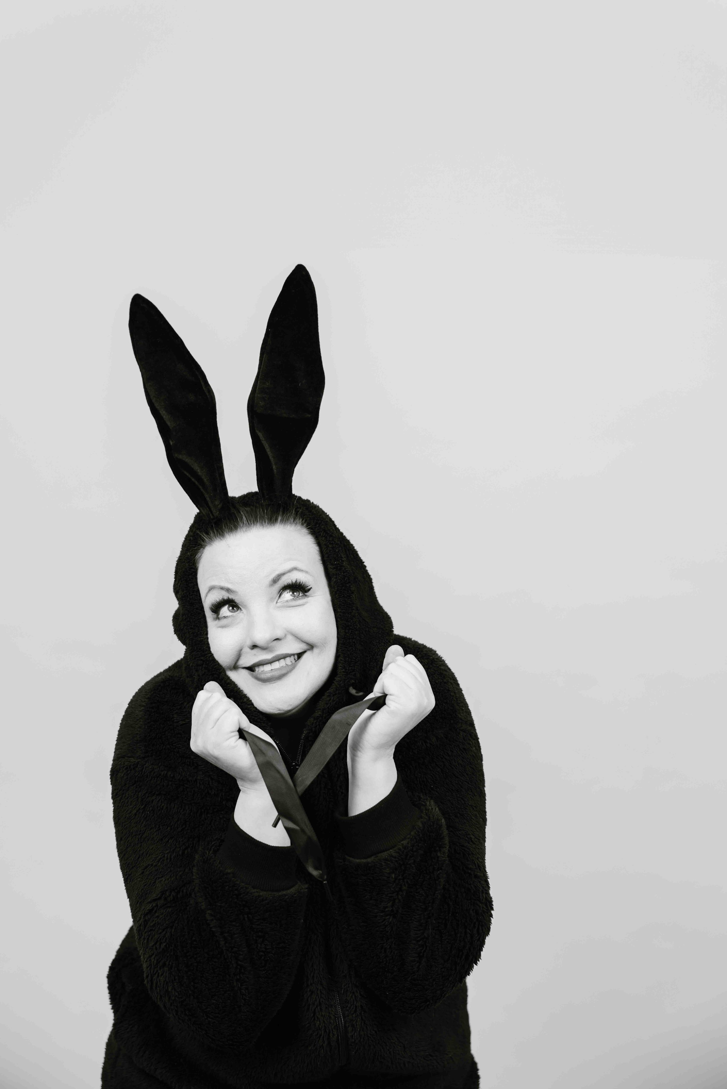 Nainen pukeutuneena jäniksen korviin ja hän hymyilee ja katsoo ylös.