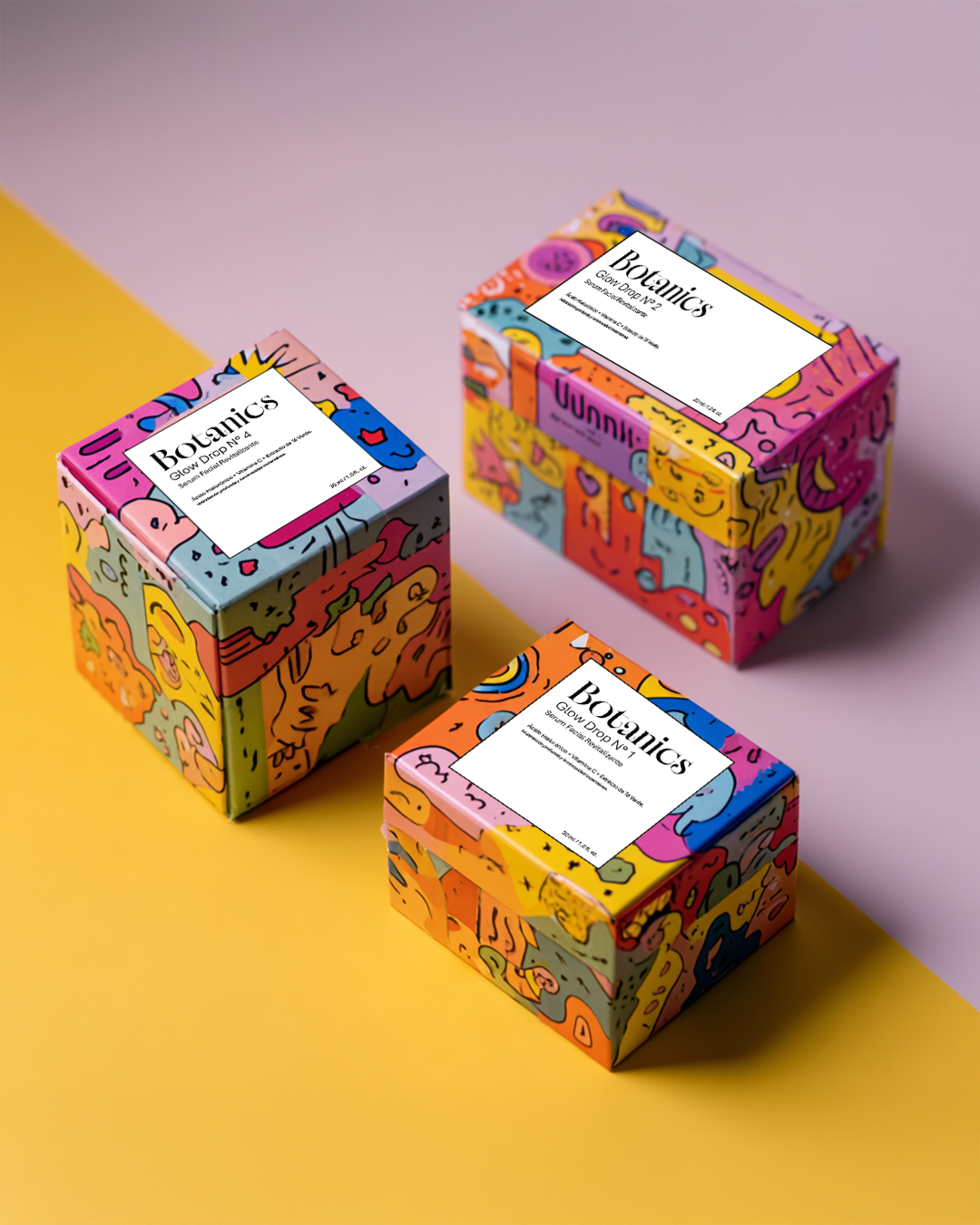 Tres cajas coloridas con ilustraciones abstractas y etiquetas que dicen 'Botanics' y 'Glow Drop' en diferentes variaciones, colocadas sobre un fondo de colores rosa y amarillo.