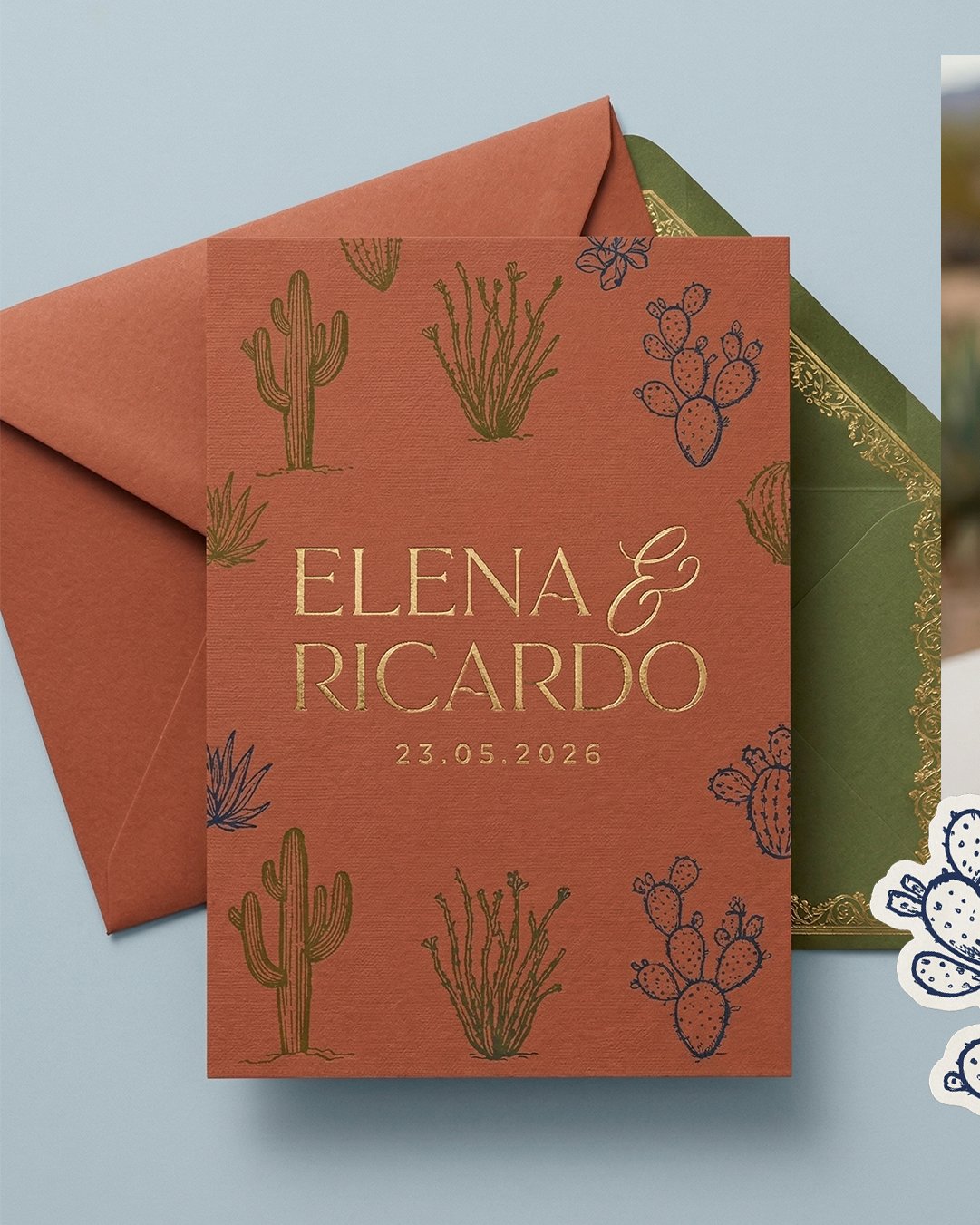 Tarjeta de invitación de boda de color terracota con ilustraciones de cactus y plantas del desierto en negro y verde, con los nombres Elena y Ricardo y la fecha 23.05.2026, acompañada de sobres de colores verde y marrón claro.