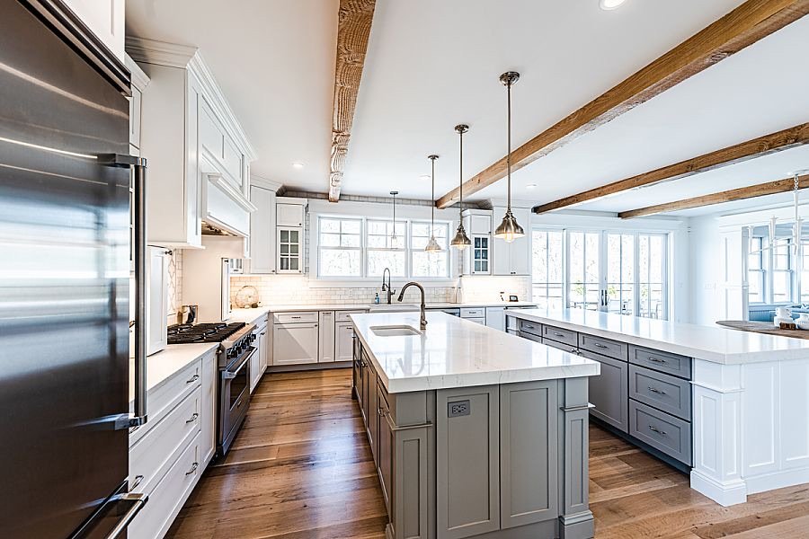 Bright, modern kitchen with white cabinets, a central island, stainless steel appliances, hardwood floors, and large windows with natural light.