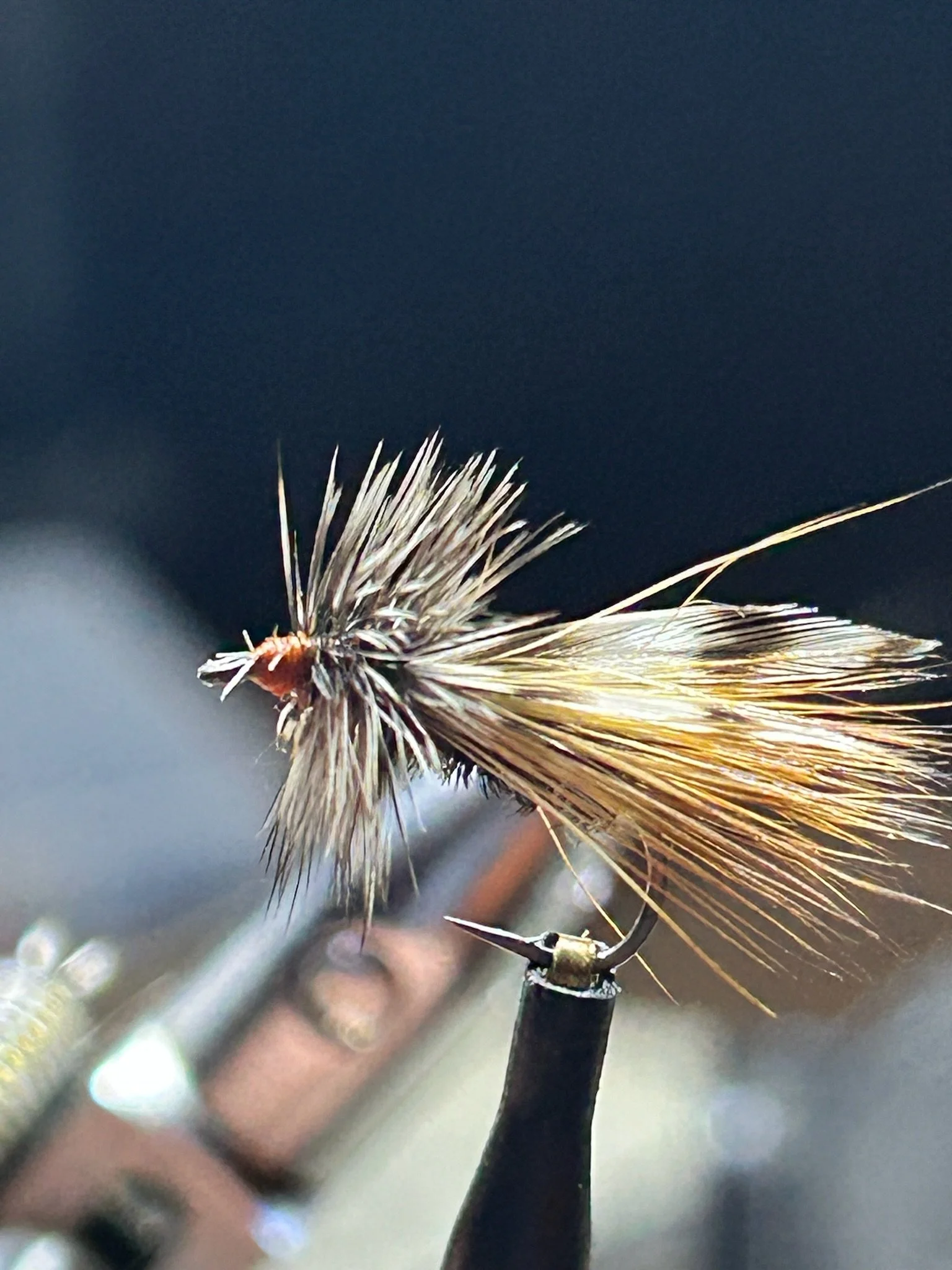 Close-up of a fishing fly used for fly fishing, with feather and fur details, attached to a fishing hook.