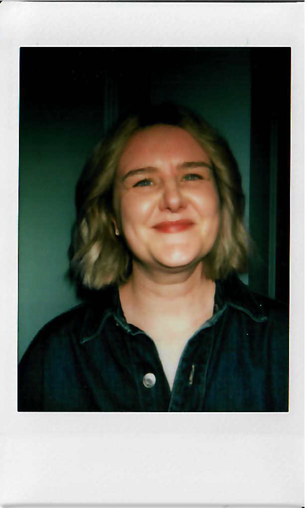 A woman with shoulder-length wavy blonde hair smiling in a Polaroid-style photo.