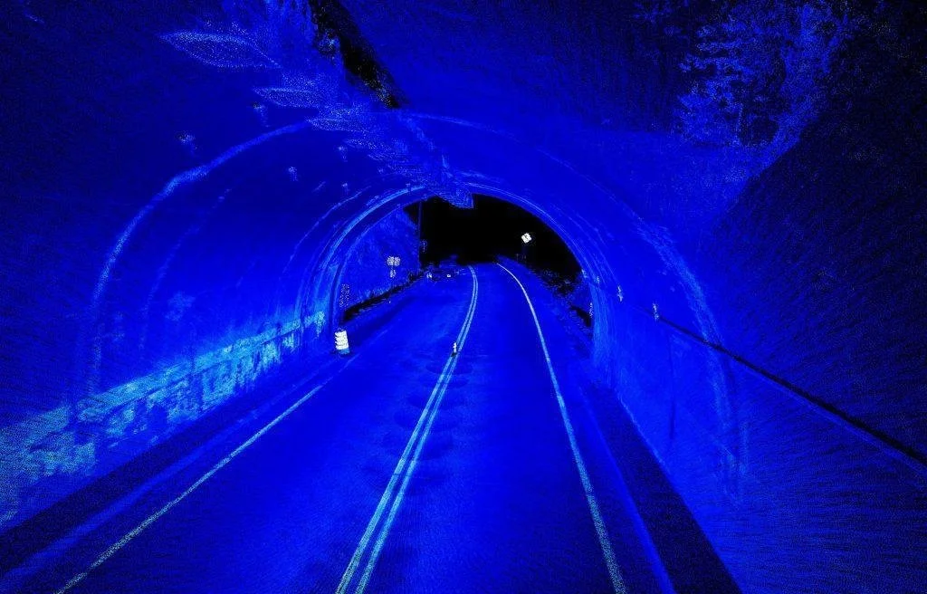 A road inside a tunnel illuminated with blue lights at night.
