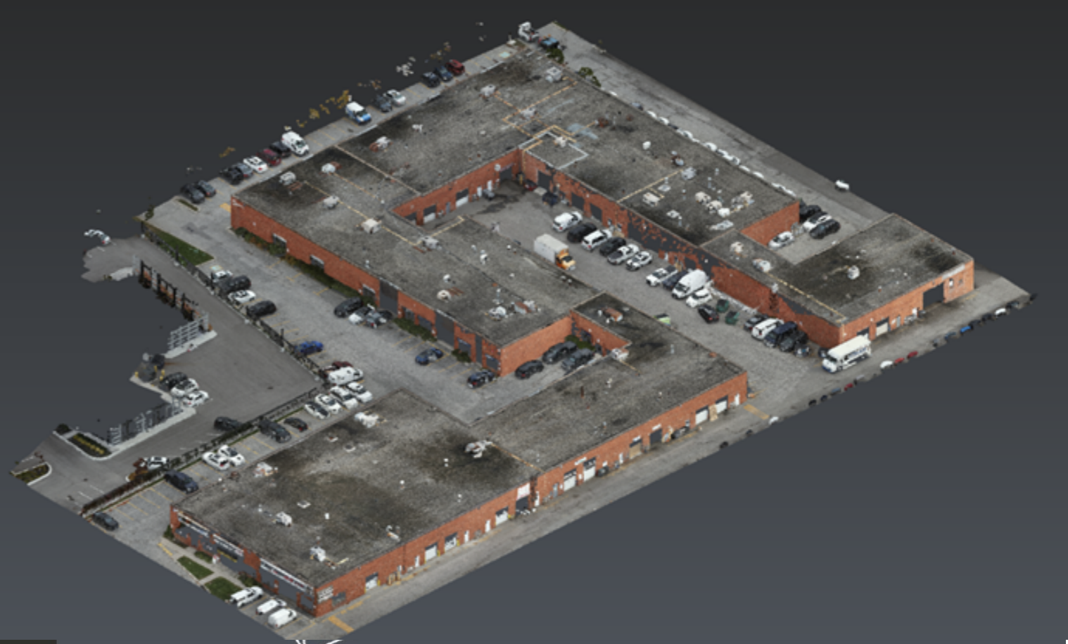 Aerial view of a large brick building with parking lots and vehicles surrounding it.