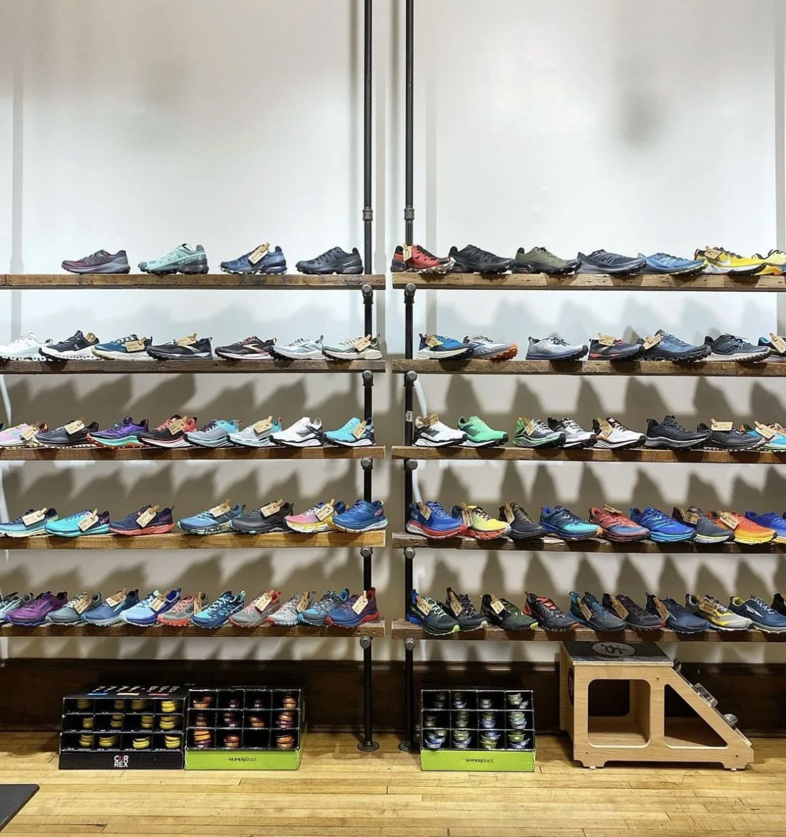 Display of various athletic shoes on wooden shelves in a retail store.