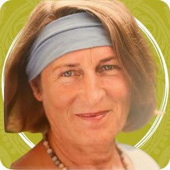 Ein Porträt einer älteren Frau mit braunen Haaren, die eine graue Stirnband trägt, vor einem grünen Hintergrund.