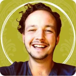 Ein fröhlicher Mann mit dunklen, lockigen Haaren und einem Bart, lächelnd vor einem grünen Hintergrund.