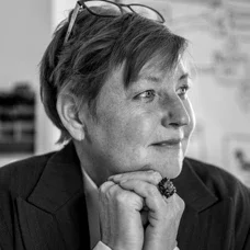 Frau mit kurzen Haaren und Brille, die nachdenklich aussieht, in Schwarz-Weiß-Fotografie