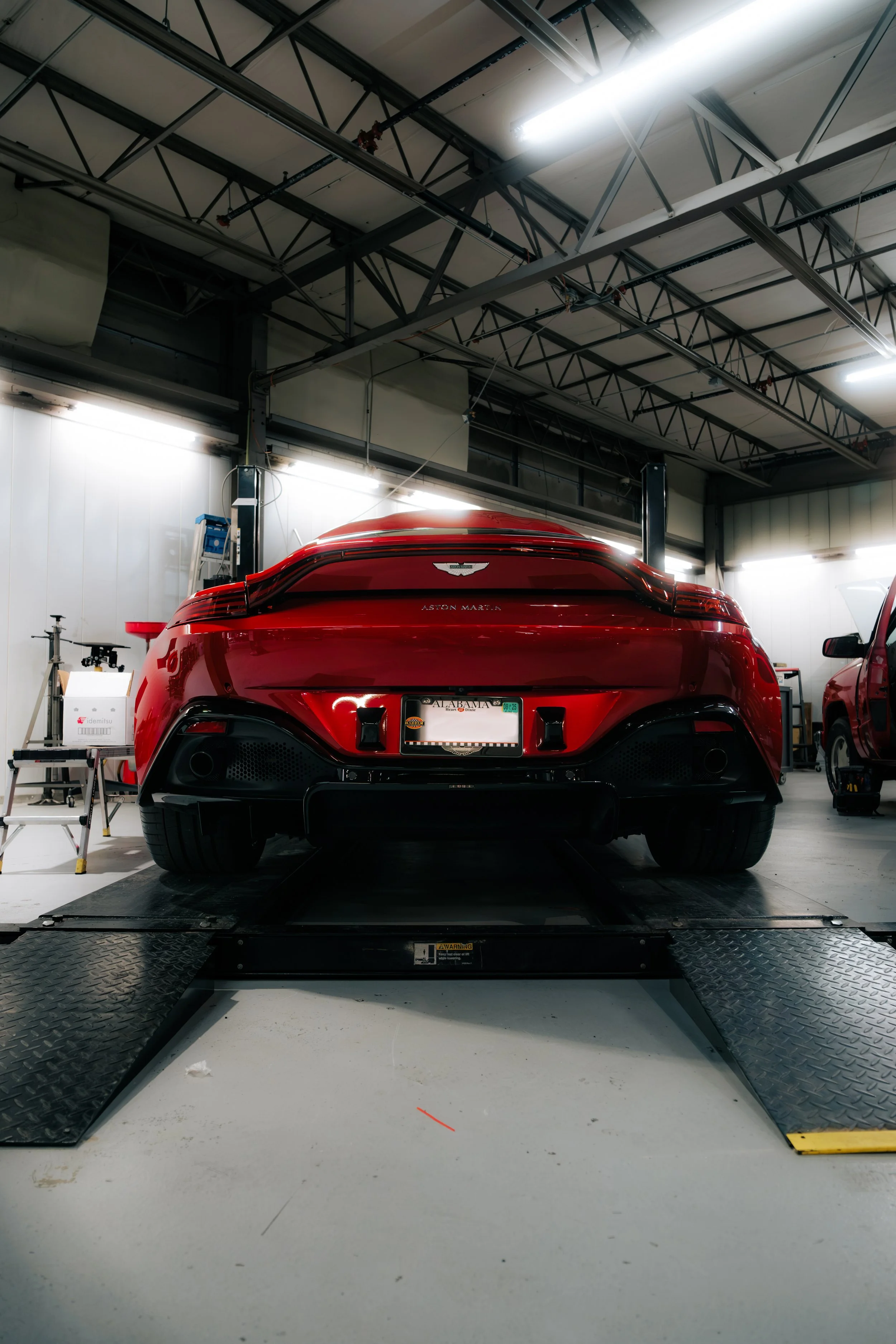 Red luxury sports car on a dynamometer inside an auto workshop.