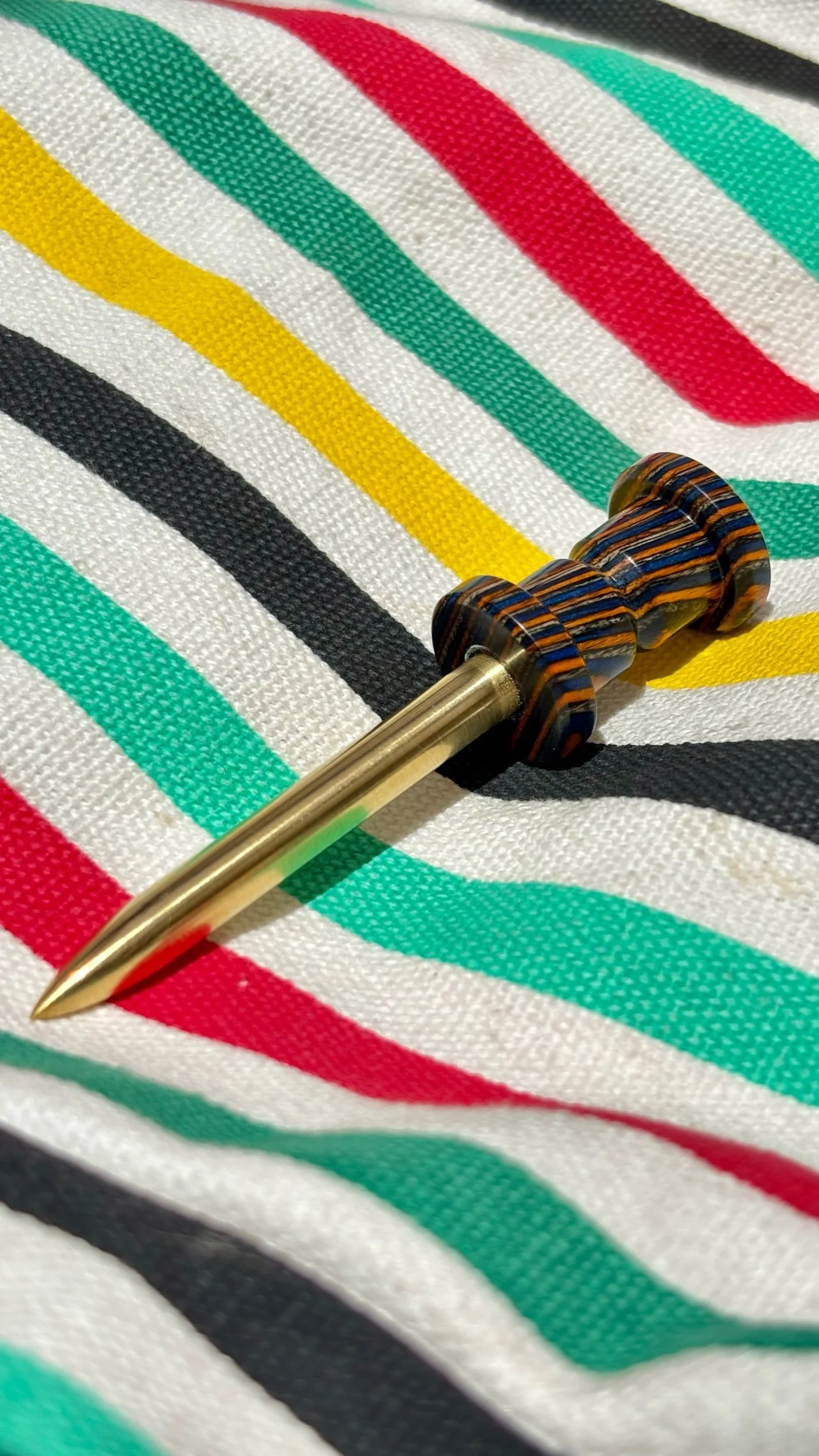The laminated maple is dyed multiple colors and features a brass prong on the divot tool