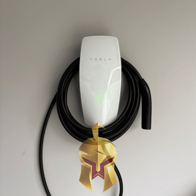 Tesla wall charger with connected charging cable on a light gray wall, featuring Spartan Home Pros Logo who specialize in EV Charging
