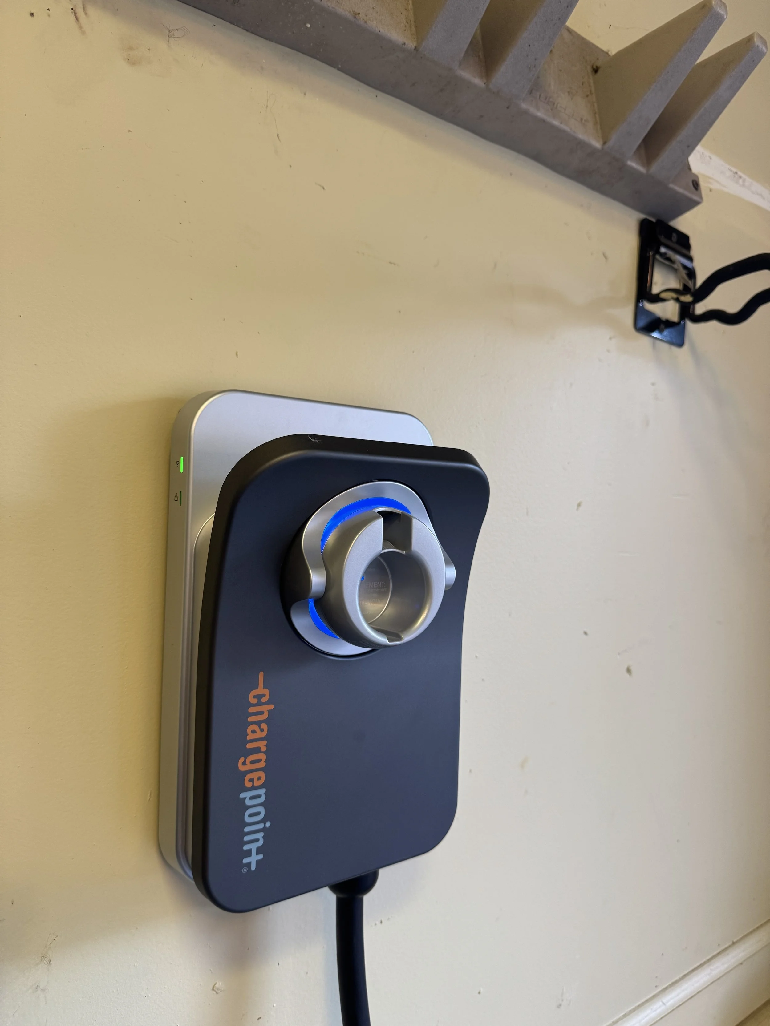 Close-up of a black and silver ChargePoint electric vehicle charger mounted on a yellow wall.