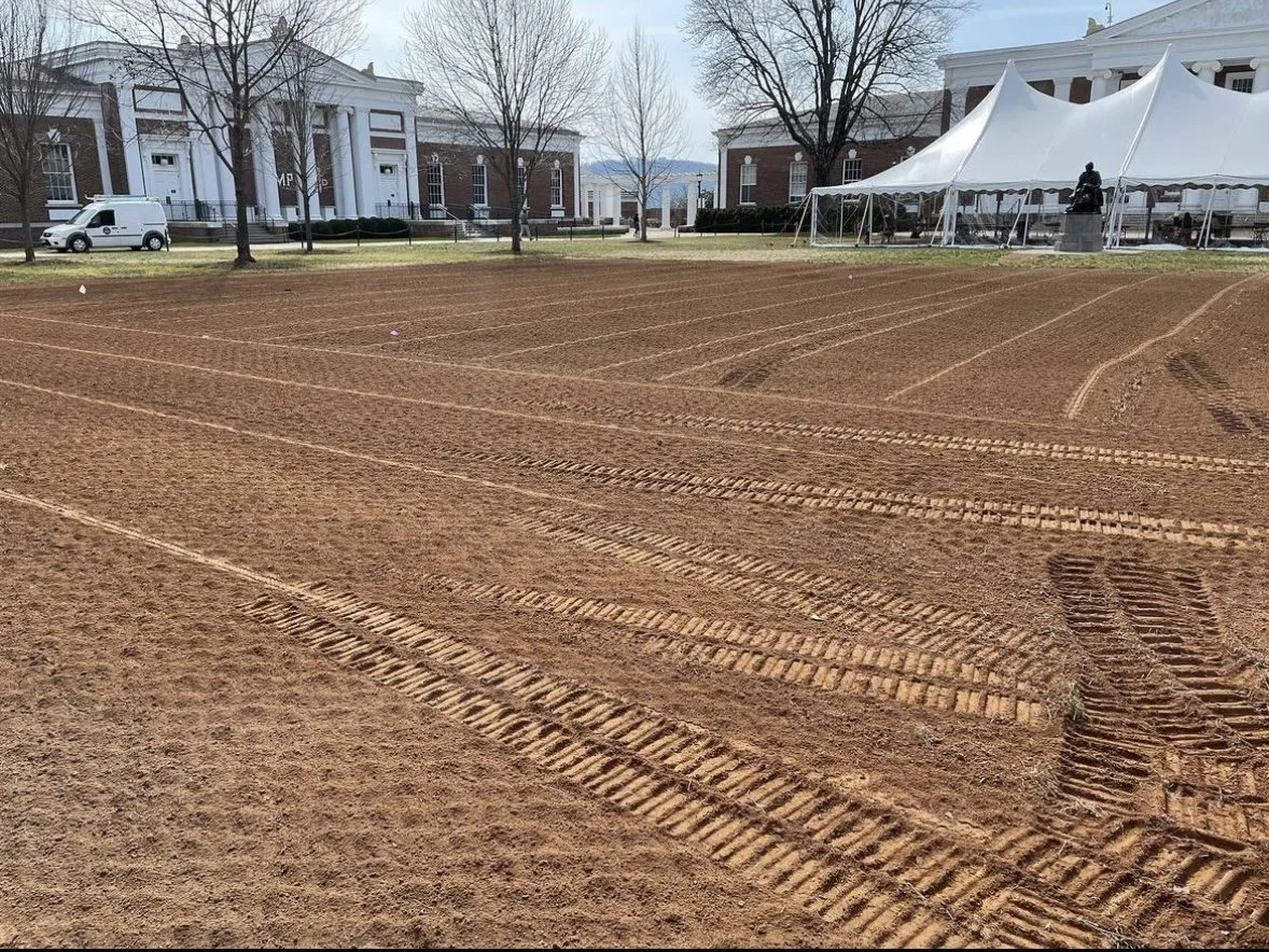 Recently prepared athletic track with vehicle and tents in the background of a campus or institutional area.