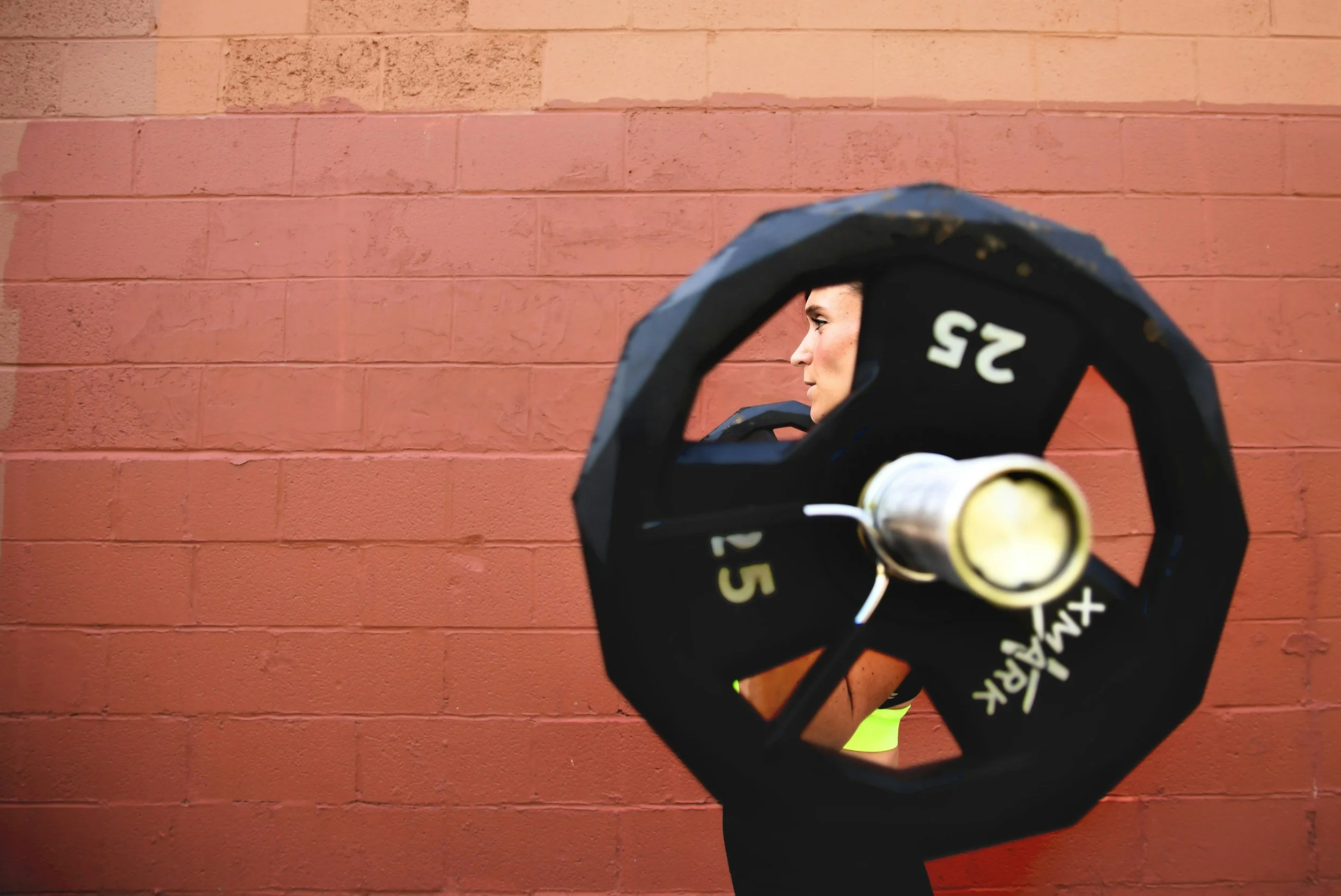 Woman lifting a barbell, symbolizing strength and how we carry weight