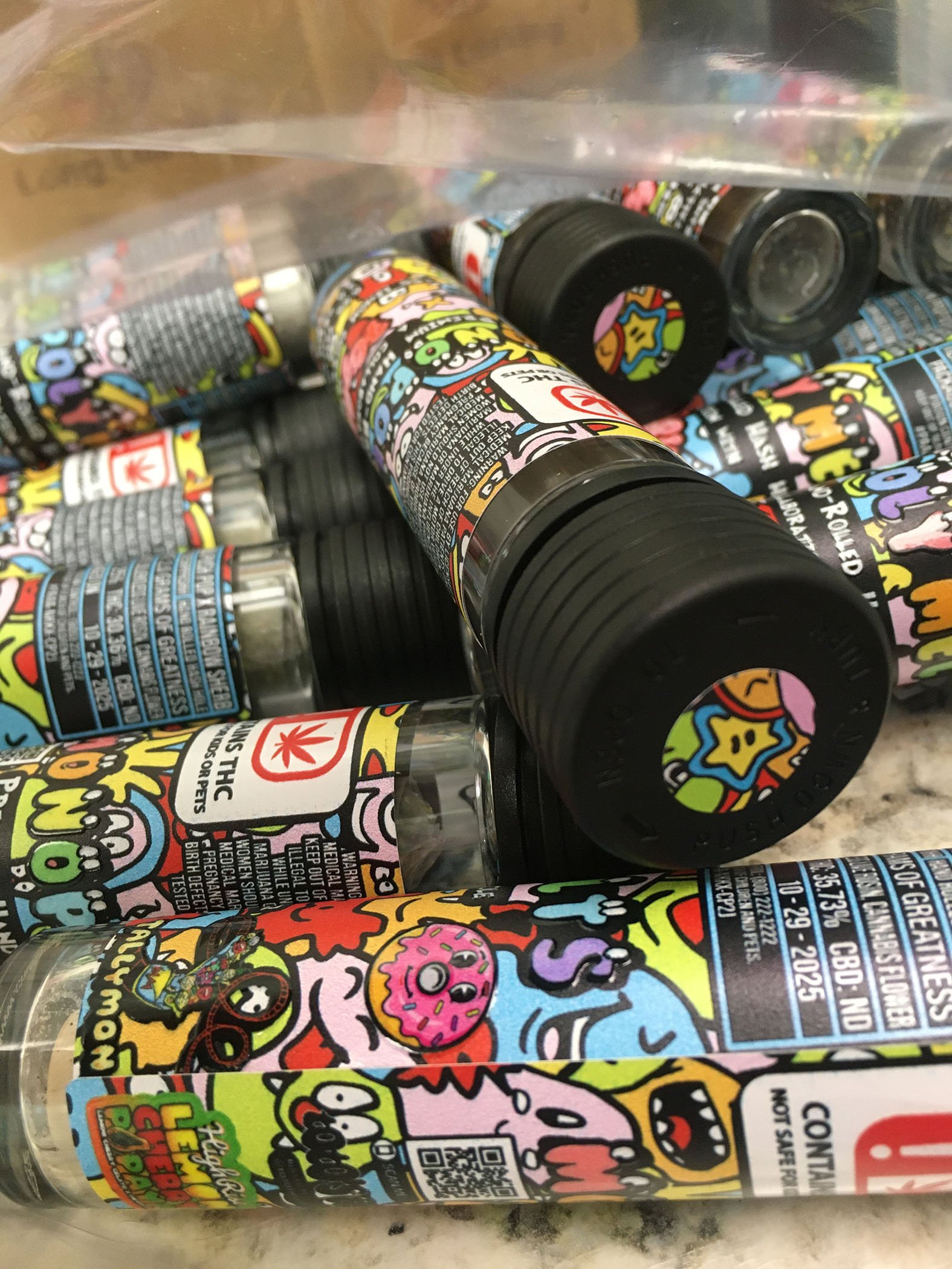 Collection of small cannabis vape cartridges with colorful cartoon-themed labels inside a plastic bag.