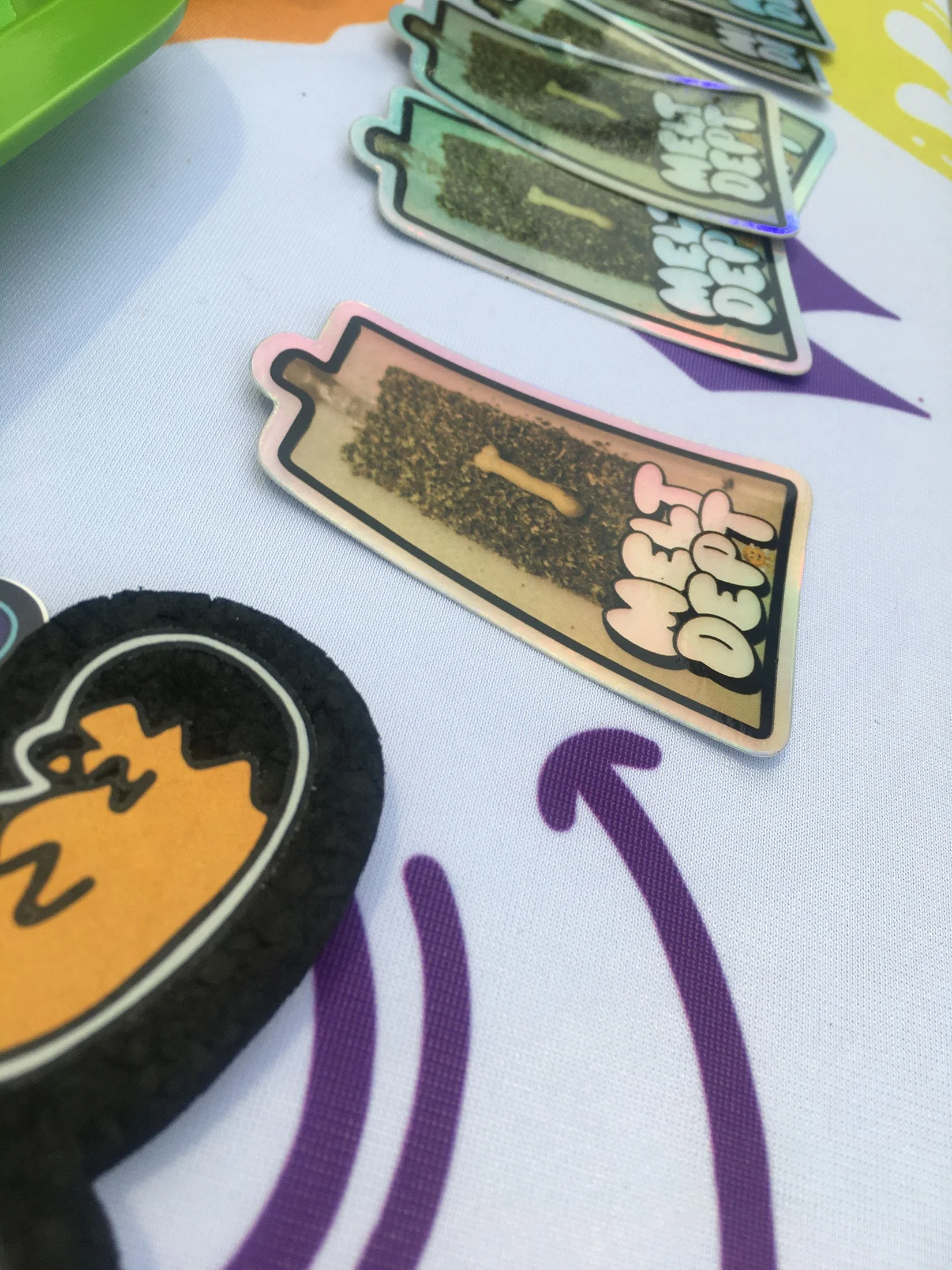 Memory card game pieces with cannabis leaf design on a white tablecloth with purple arrow graphics.