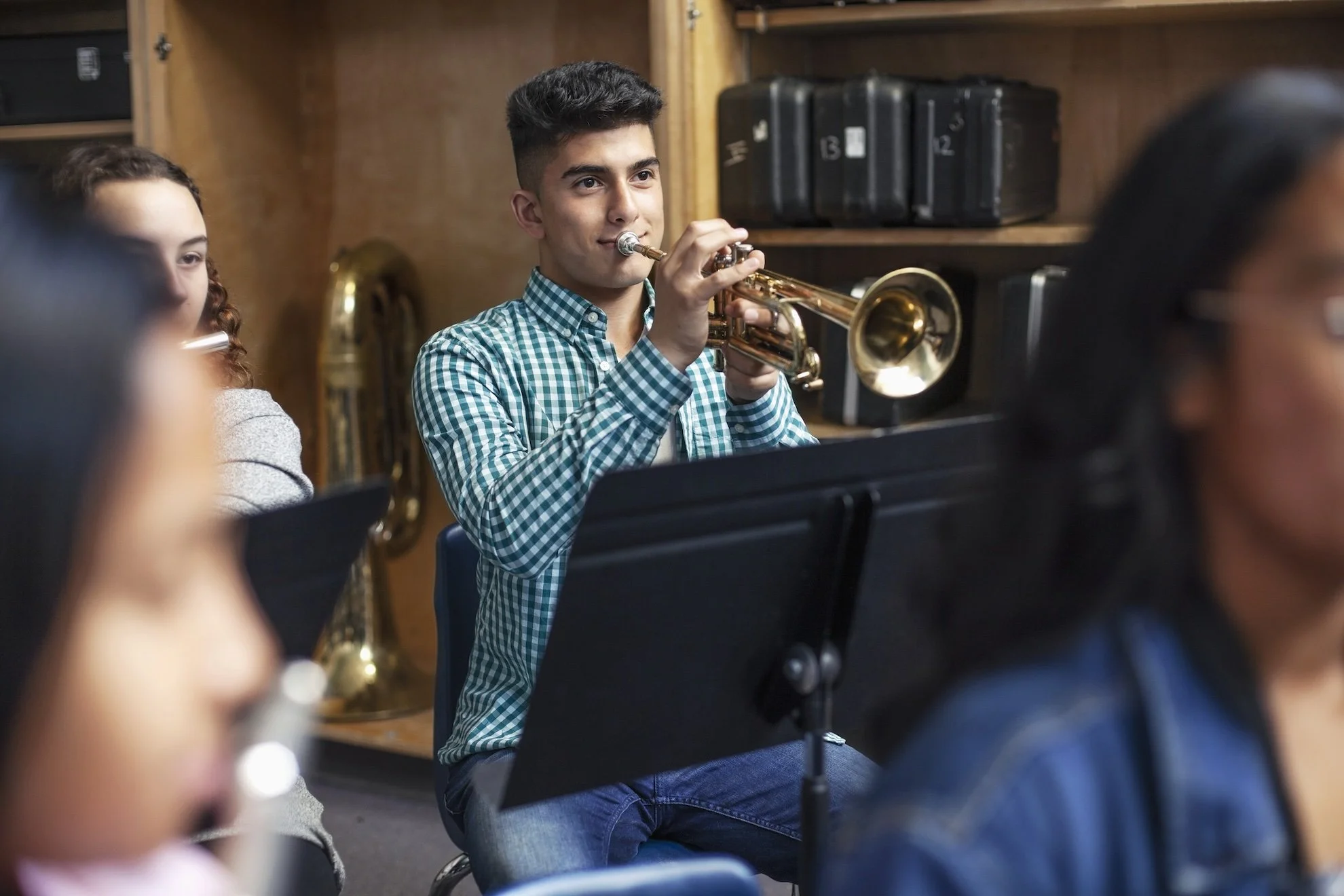 Teen male playing trumpet in band class