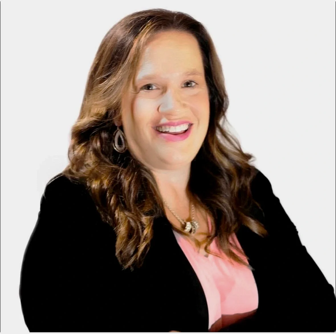 A woman with long, wavy brown hair, wearing earrings, a necklace, a pink top, and a black blazer, smiling against a plain white background.