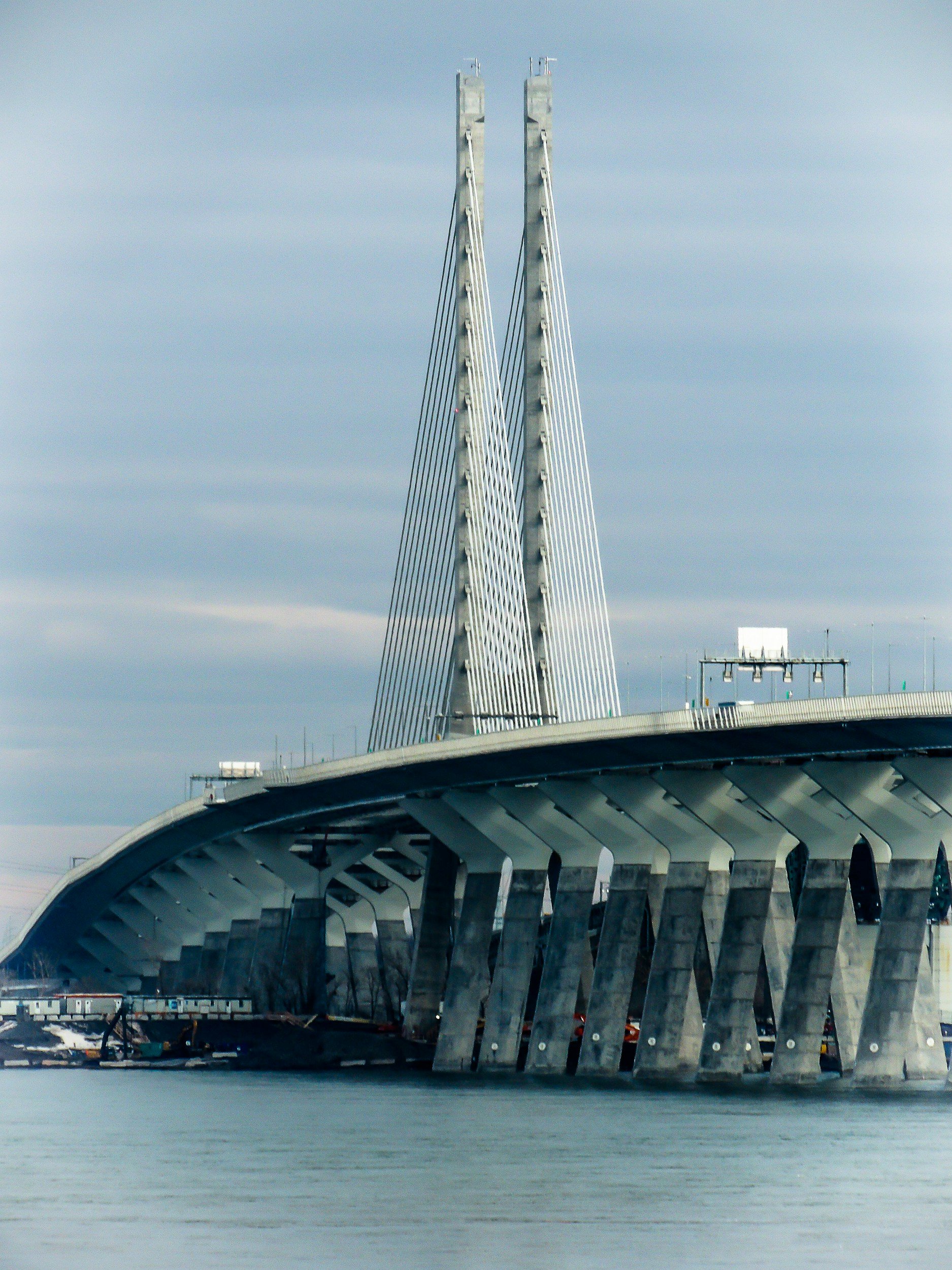 Bridge with tall pylons and multiple cables over water, with a cloudy sky in the background.