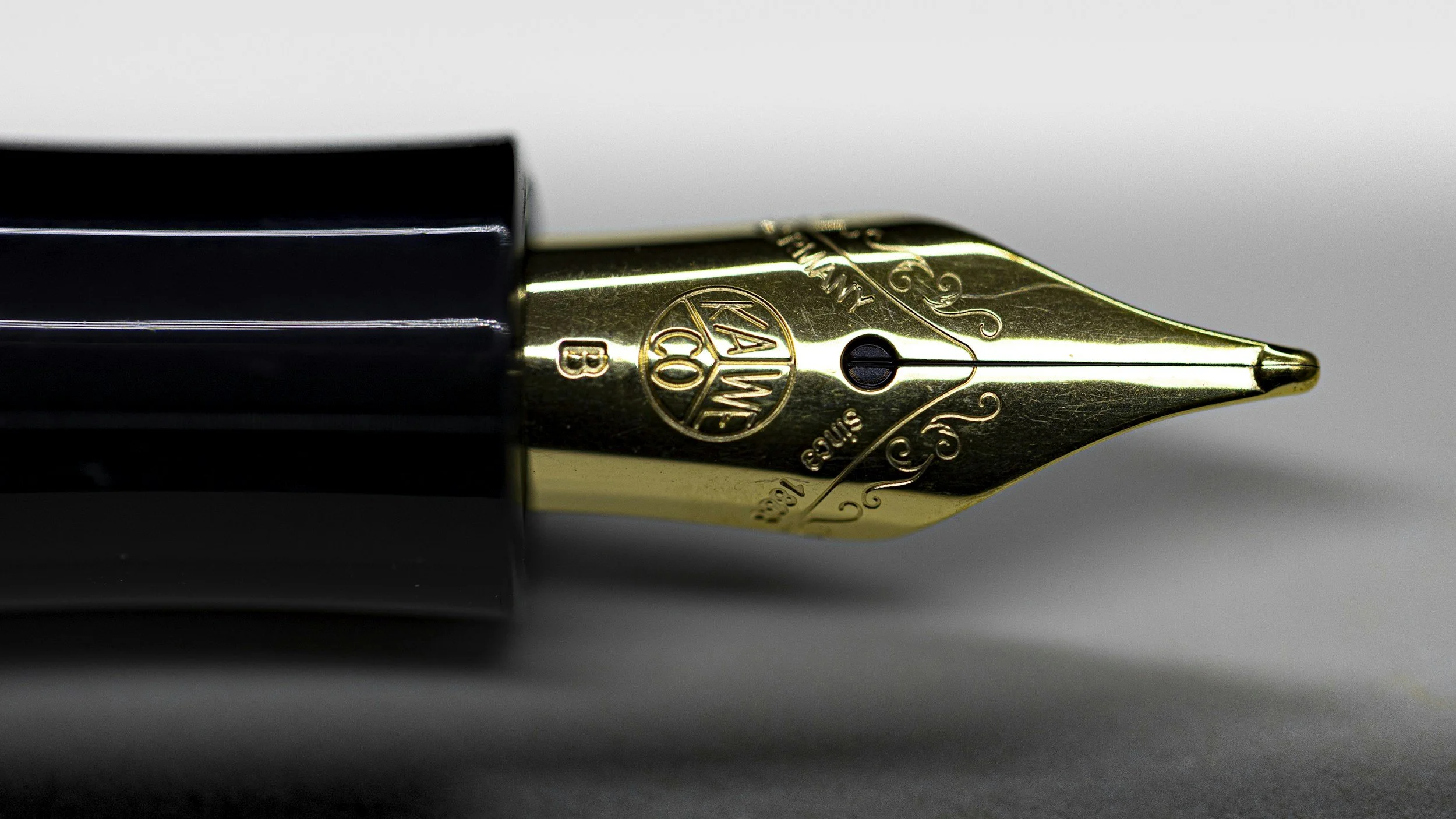 Close-up of a gold and black fountain pen nib with engraved details.